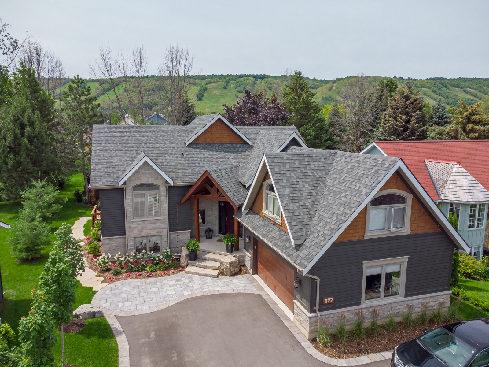Modern gray suburban home with landscaped yard and hills