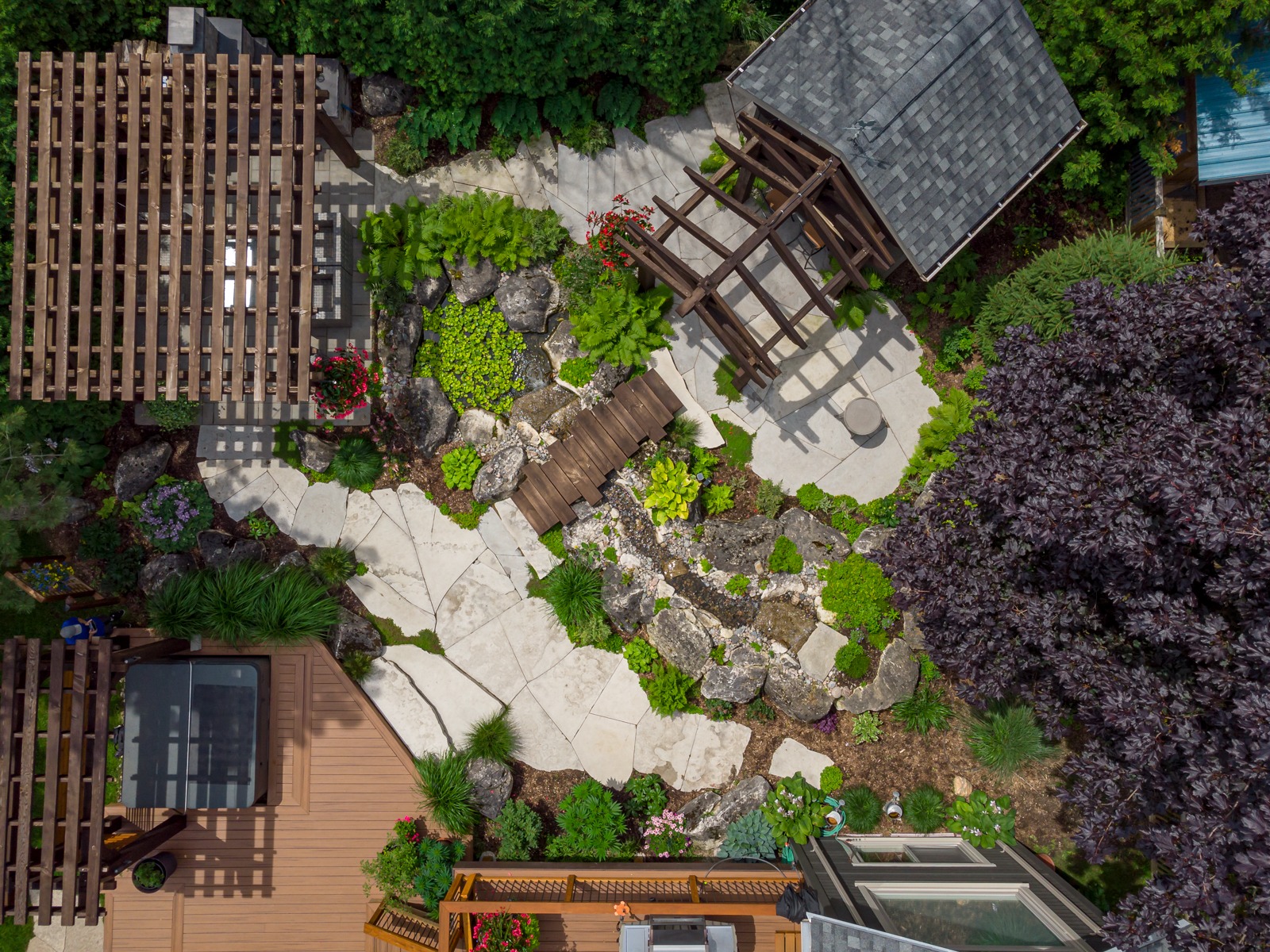 Aerial view of landscaped backyard with pergolas and pond