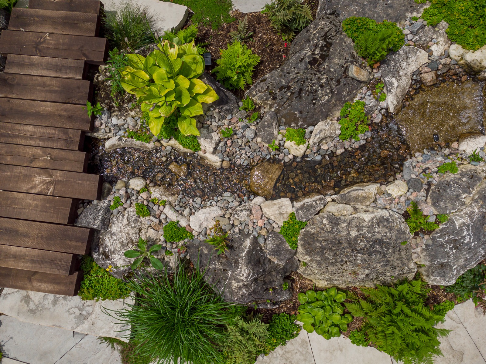 Wooden bridge over small landscaped garden stream
