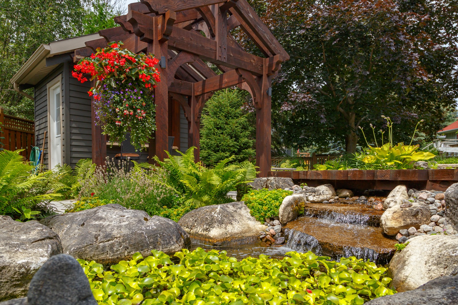 Wooden pergola over garden pond with waterfall