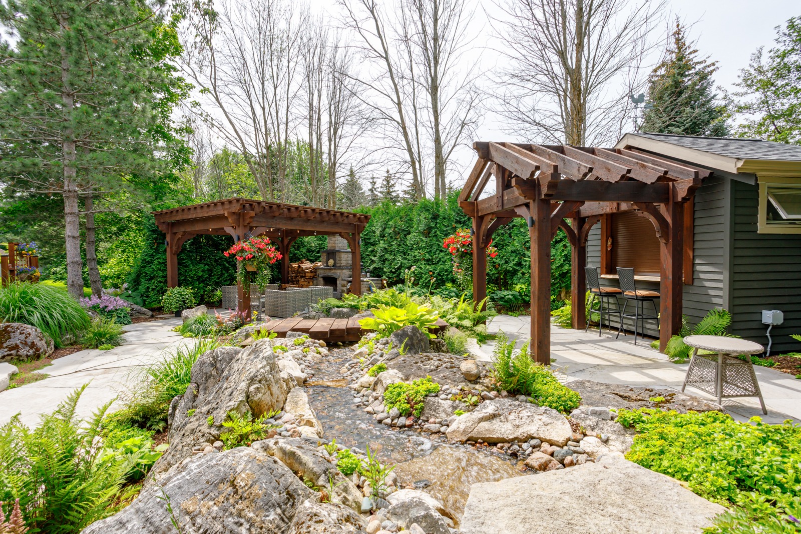 Landscaped backyard with pergolas and stone stream