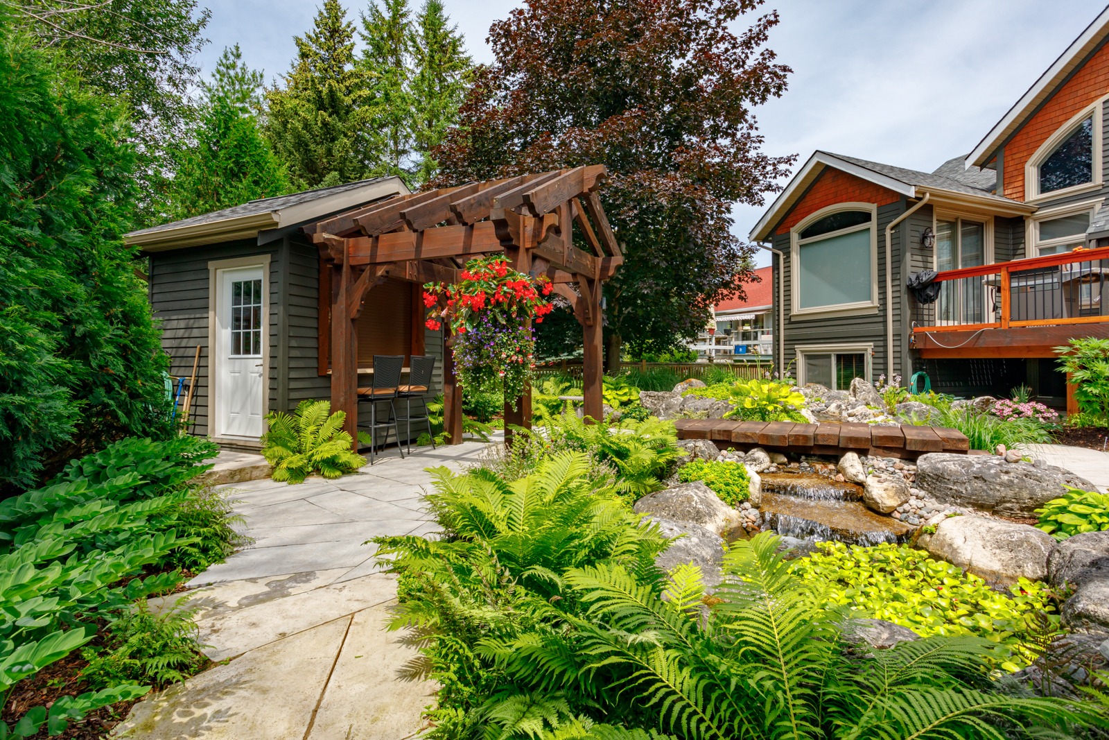 Landscaped backyard with pergola, pond, and garden shed