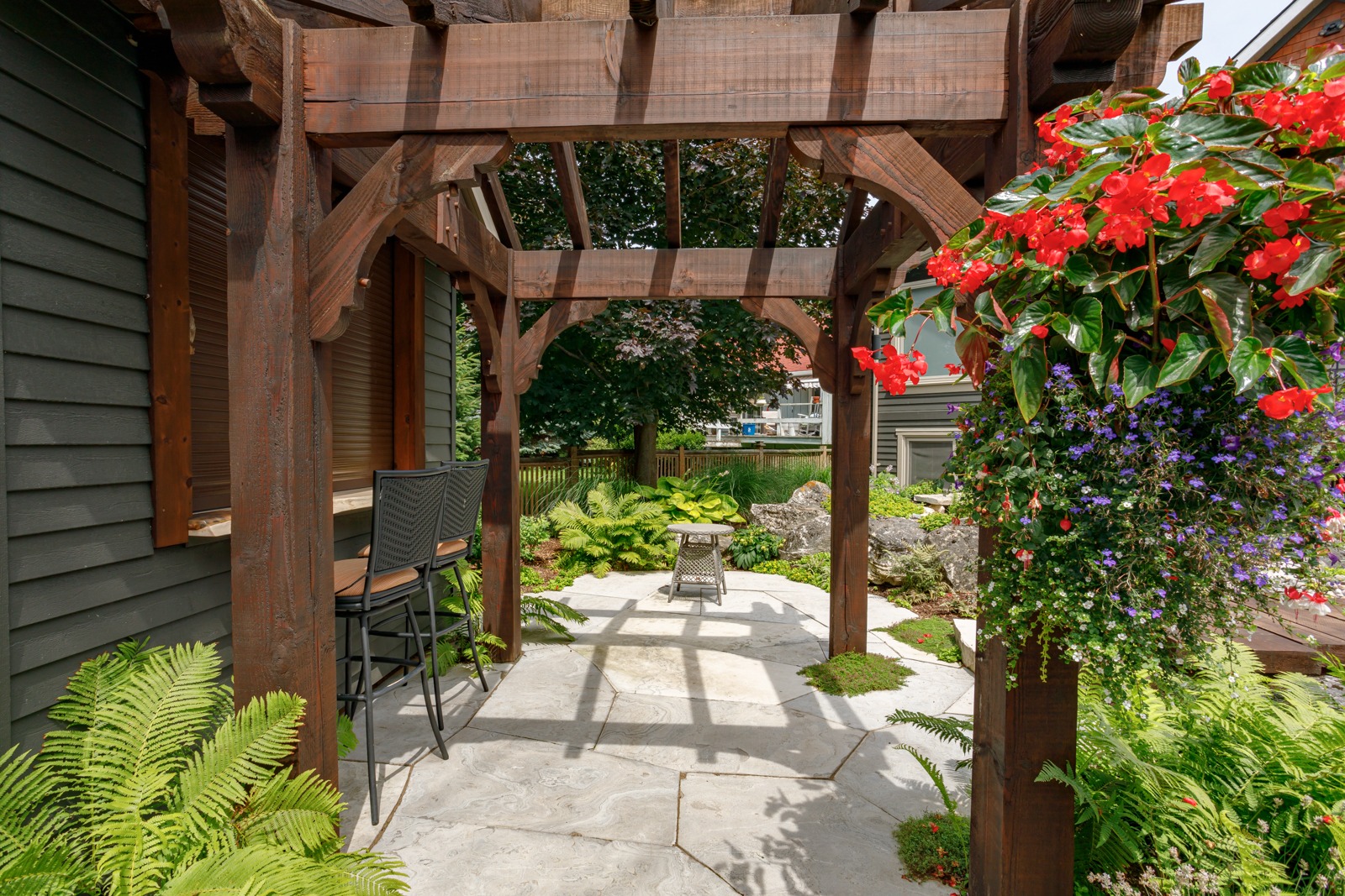 Wooden pergola over stone patio with lush garden