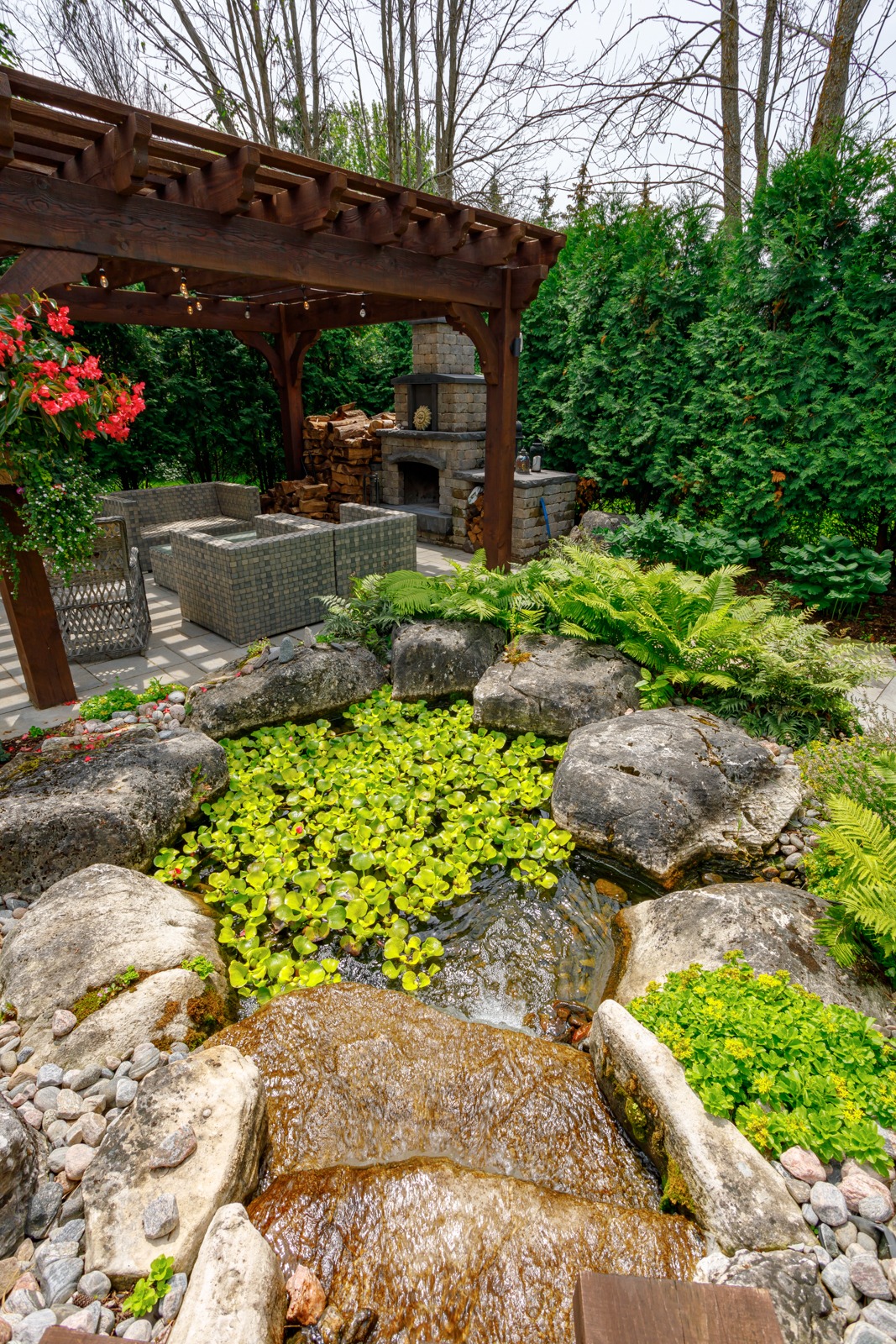 Landscaped backyard with pergola, fireplace, and pond