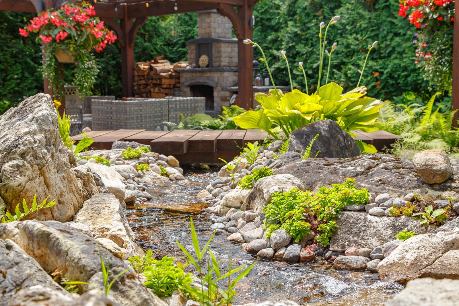 Landscaped backyard with stream, bridge, and pergola