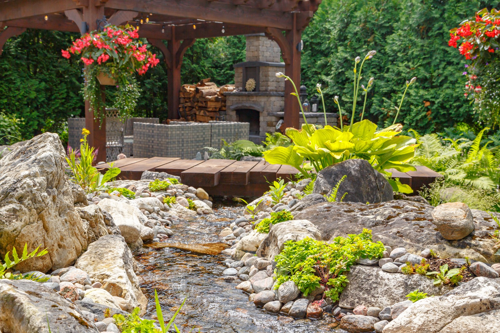 Landscaped backyard with stream, bridge, and pergola
