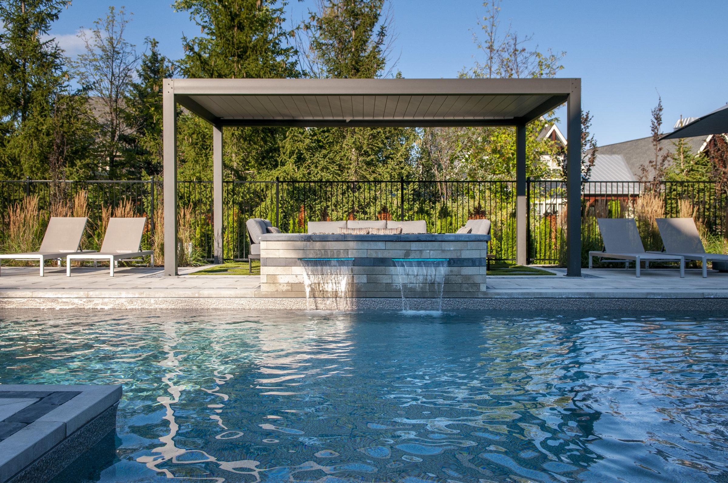 Modern backyard pool with pergola and waterfall feature