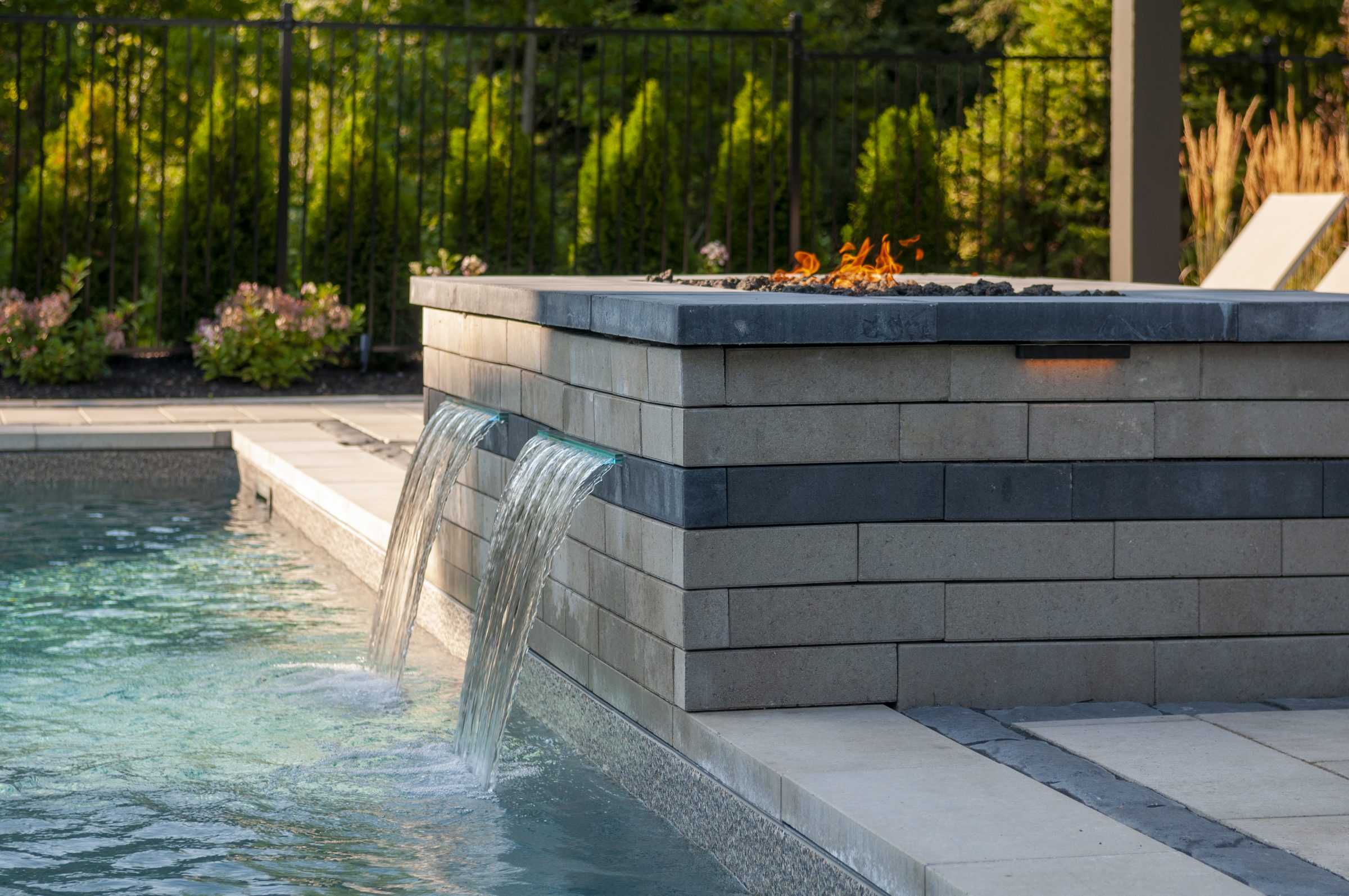 Modern pool with waterfall features and fire pit