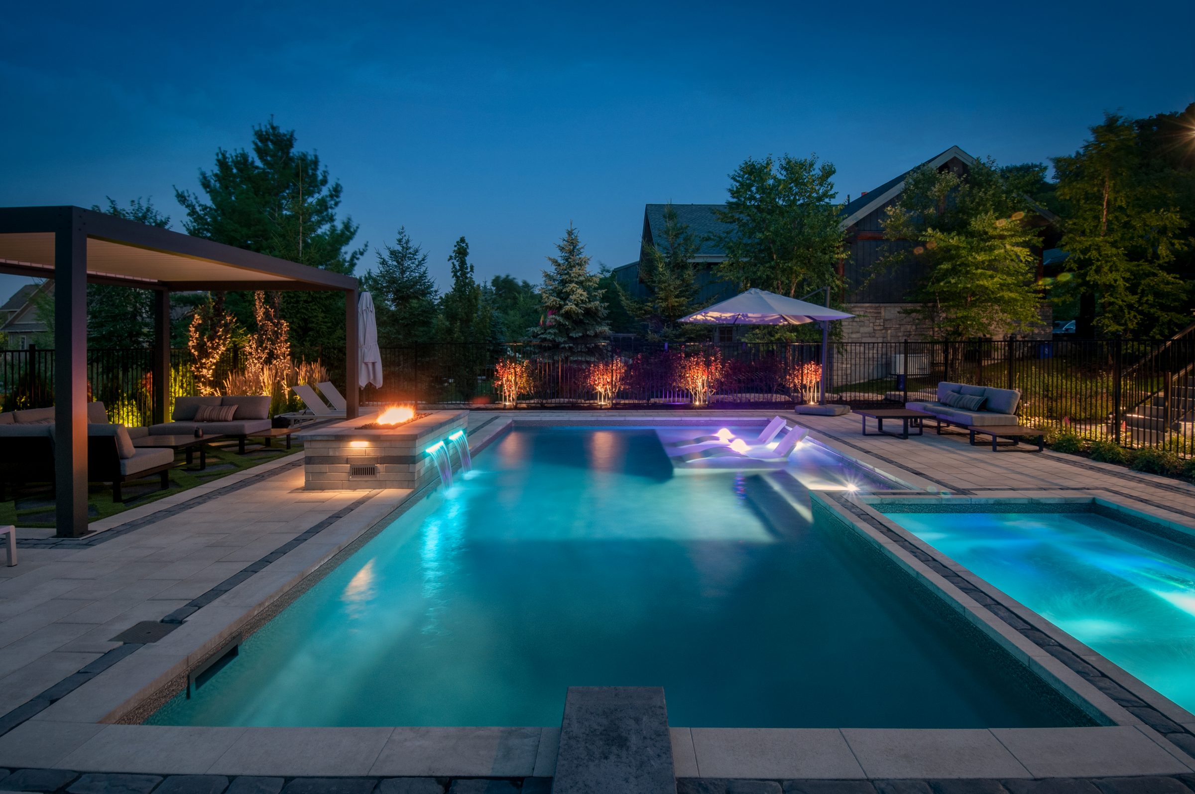 Modern backyard pool with fire pit at dusk