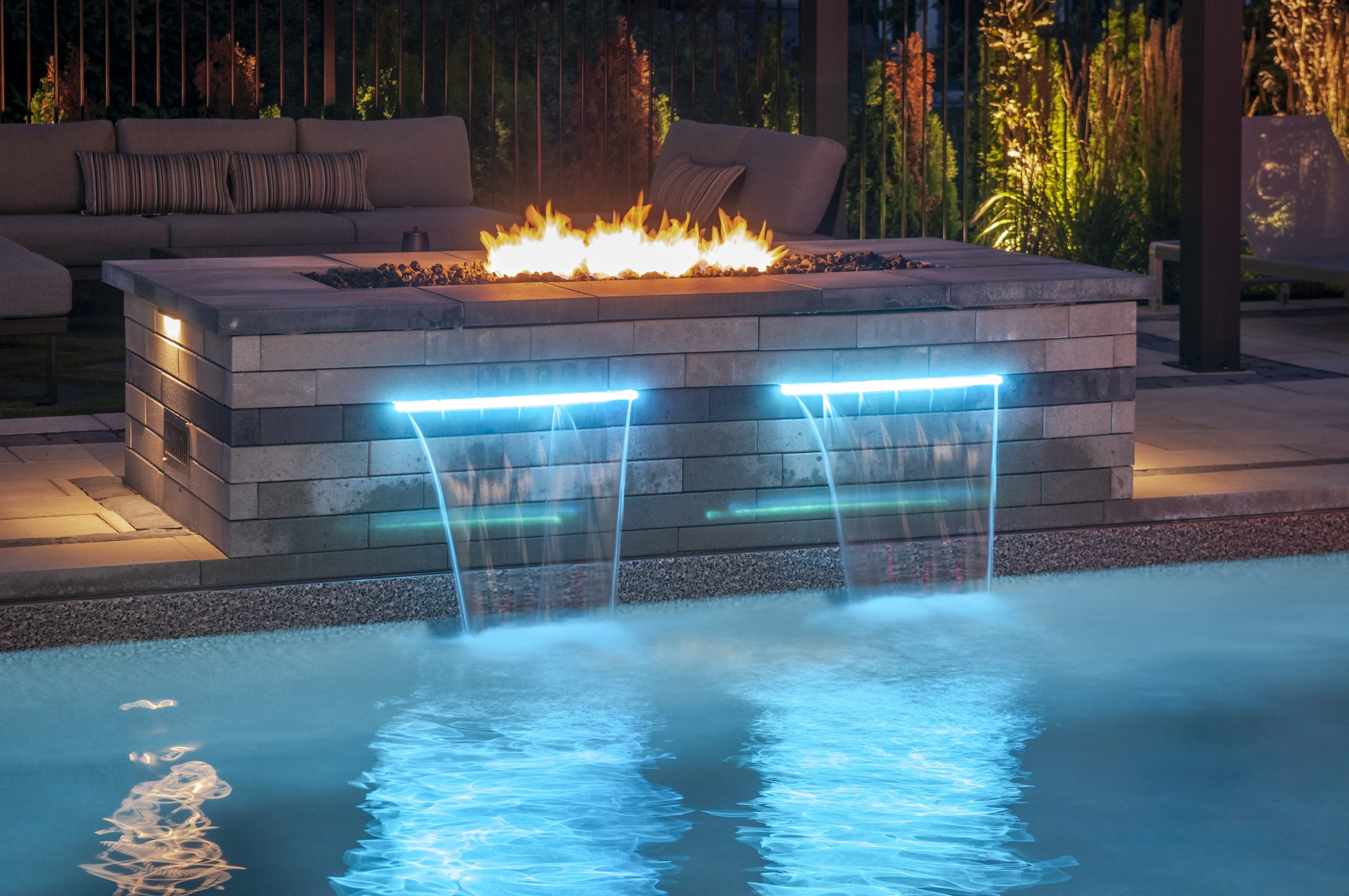 Modern backyard pool with fire pit and waterfalls