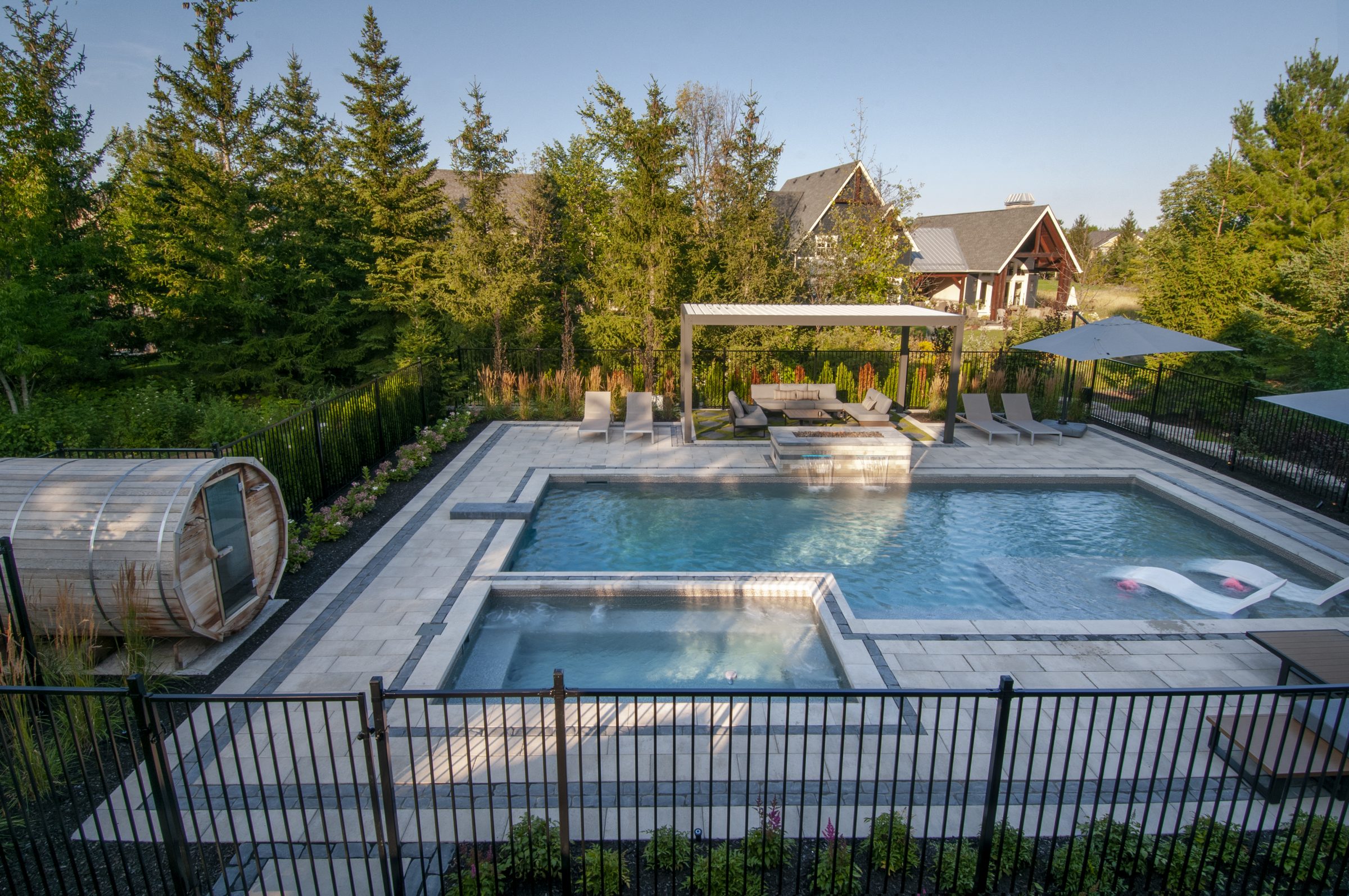 Modern backyard pool with spa and patio seating