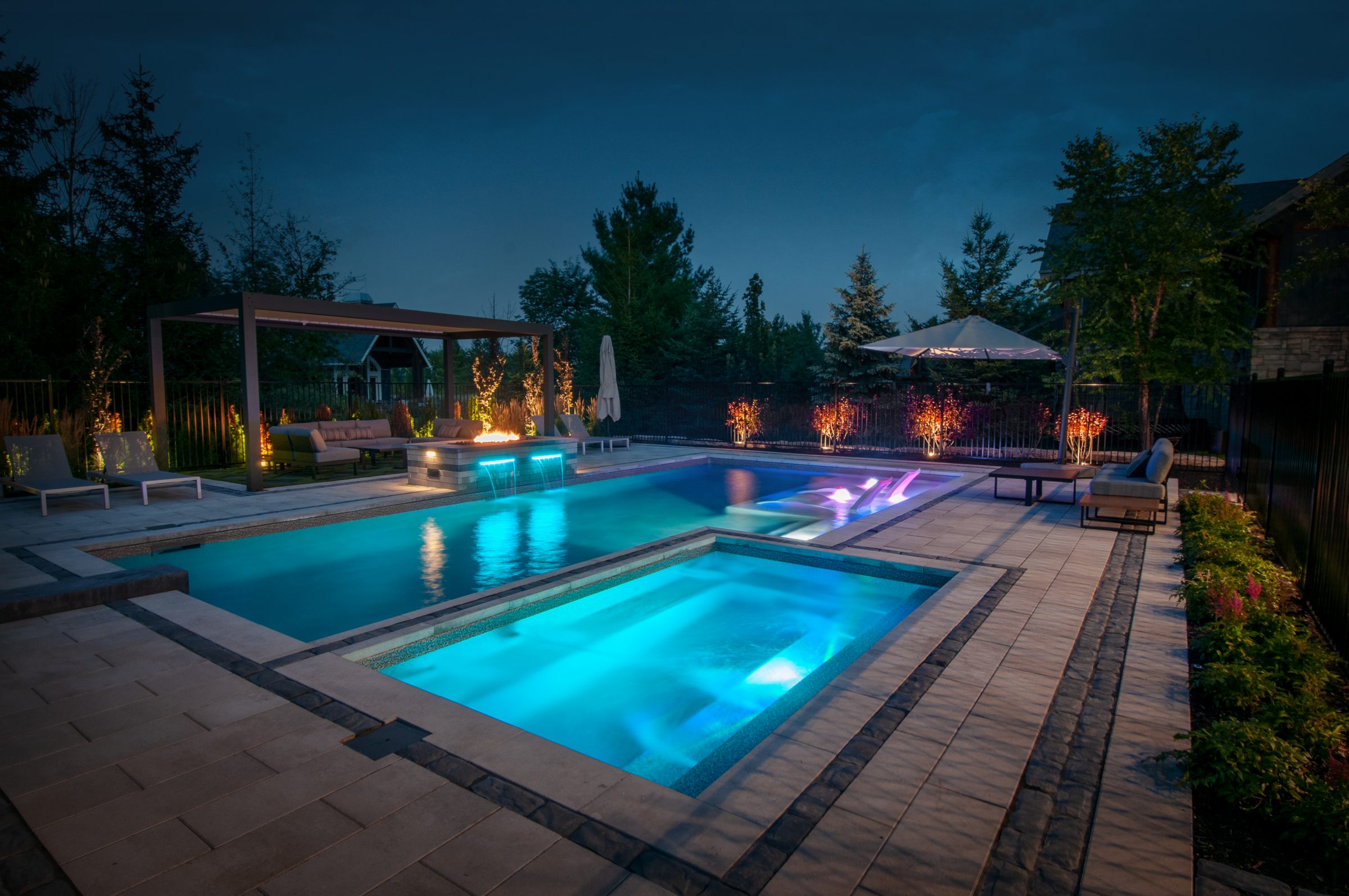 Modern backyard pool and spa at night