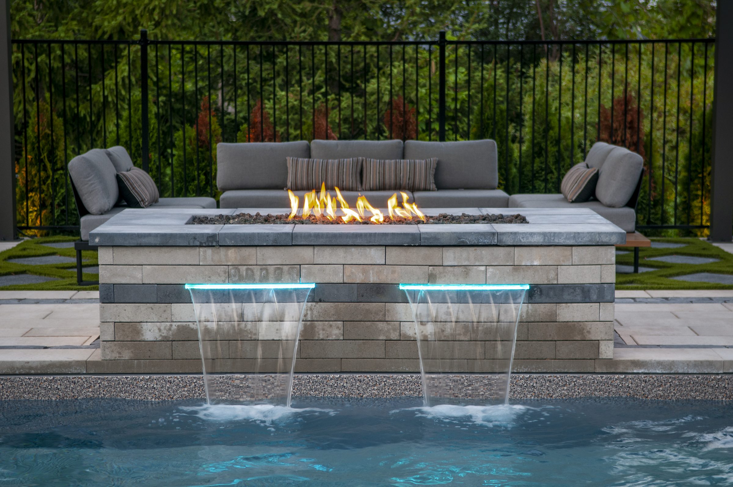 Modern backyard fire pit with pool waterfalls