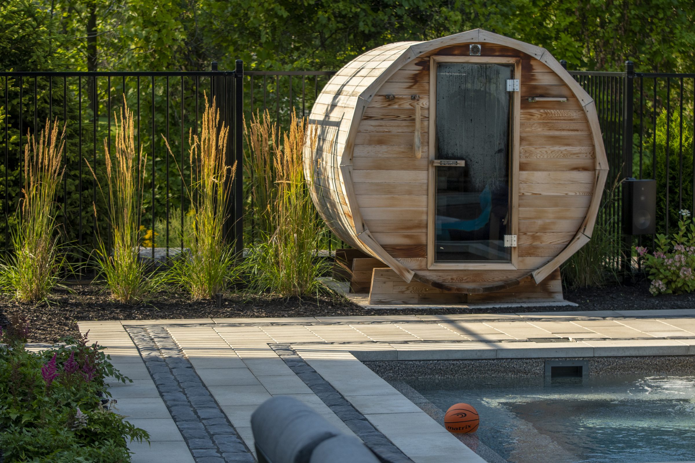 Outdoor barrel sauna beside backyard swimming pool