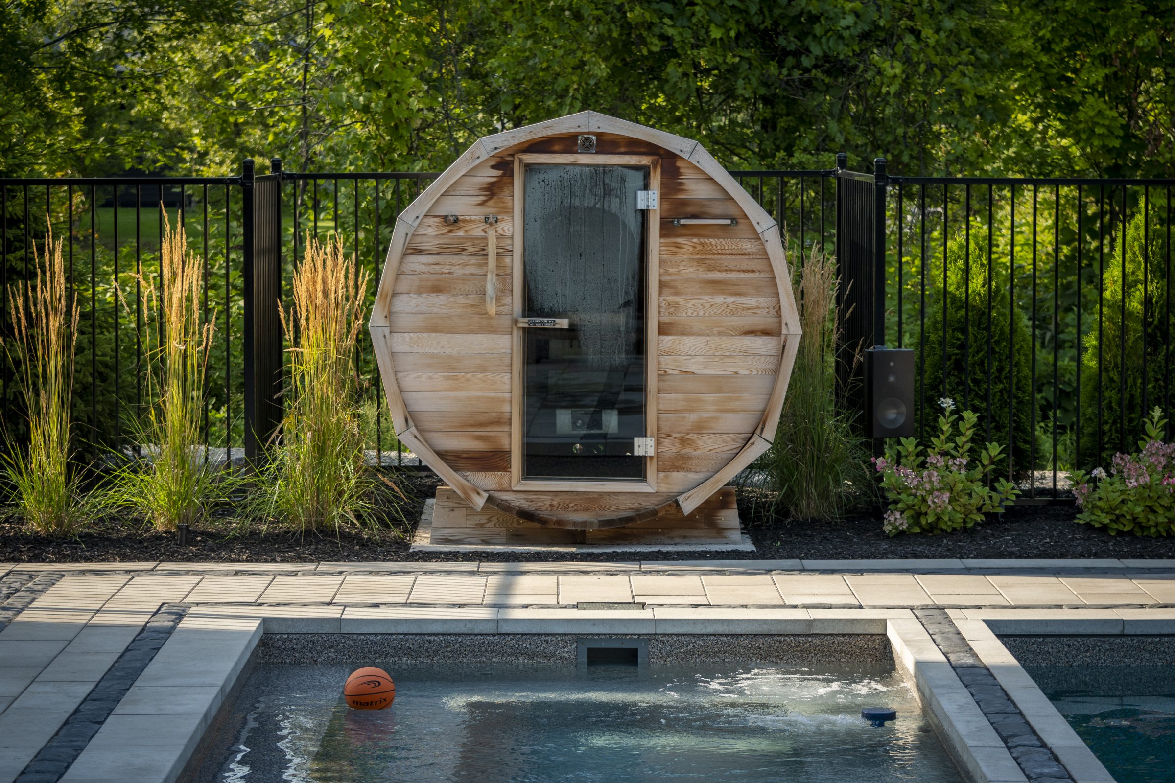 Outdoor barrel sauna beside backyard swimming pool