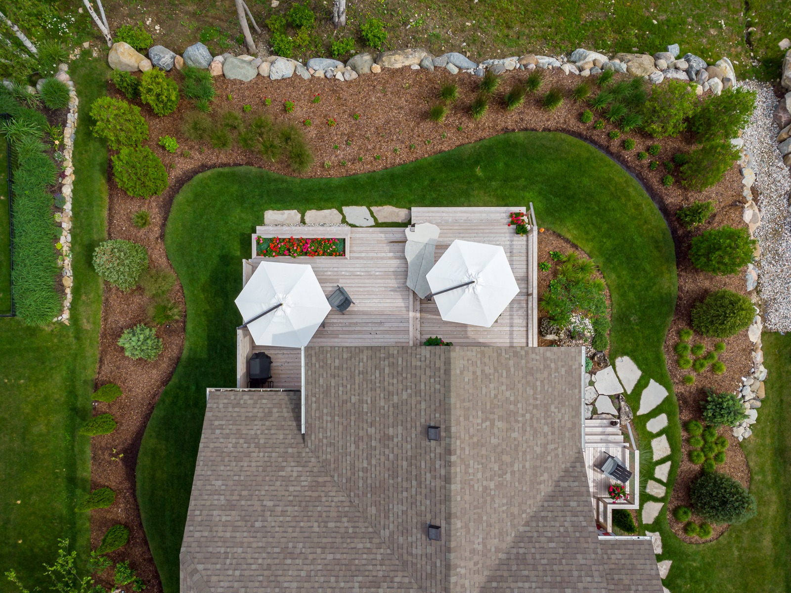 Aerial view of landscaped backyard with deck and umbrellas