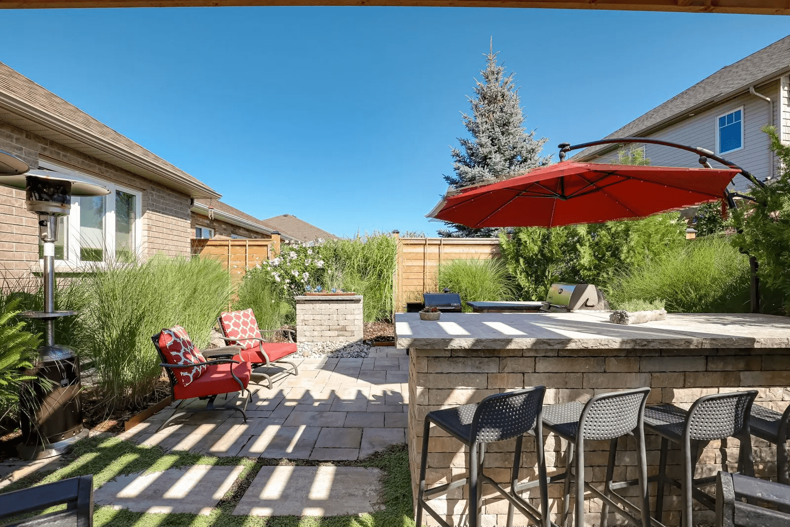 Backyard patio with outdoor kitchen and red umbrella