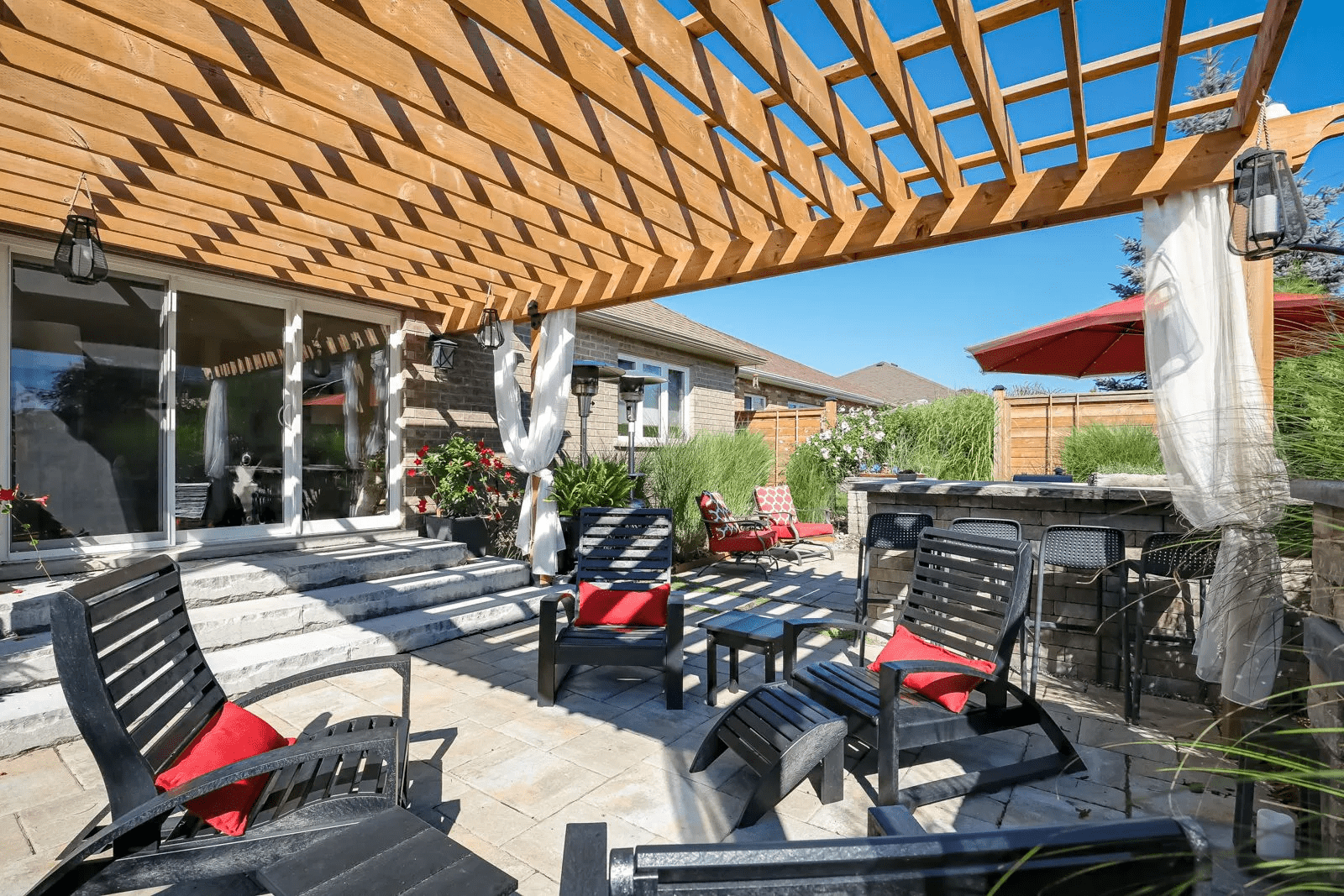 Backyard patio with pergola and red cushioned chairs