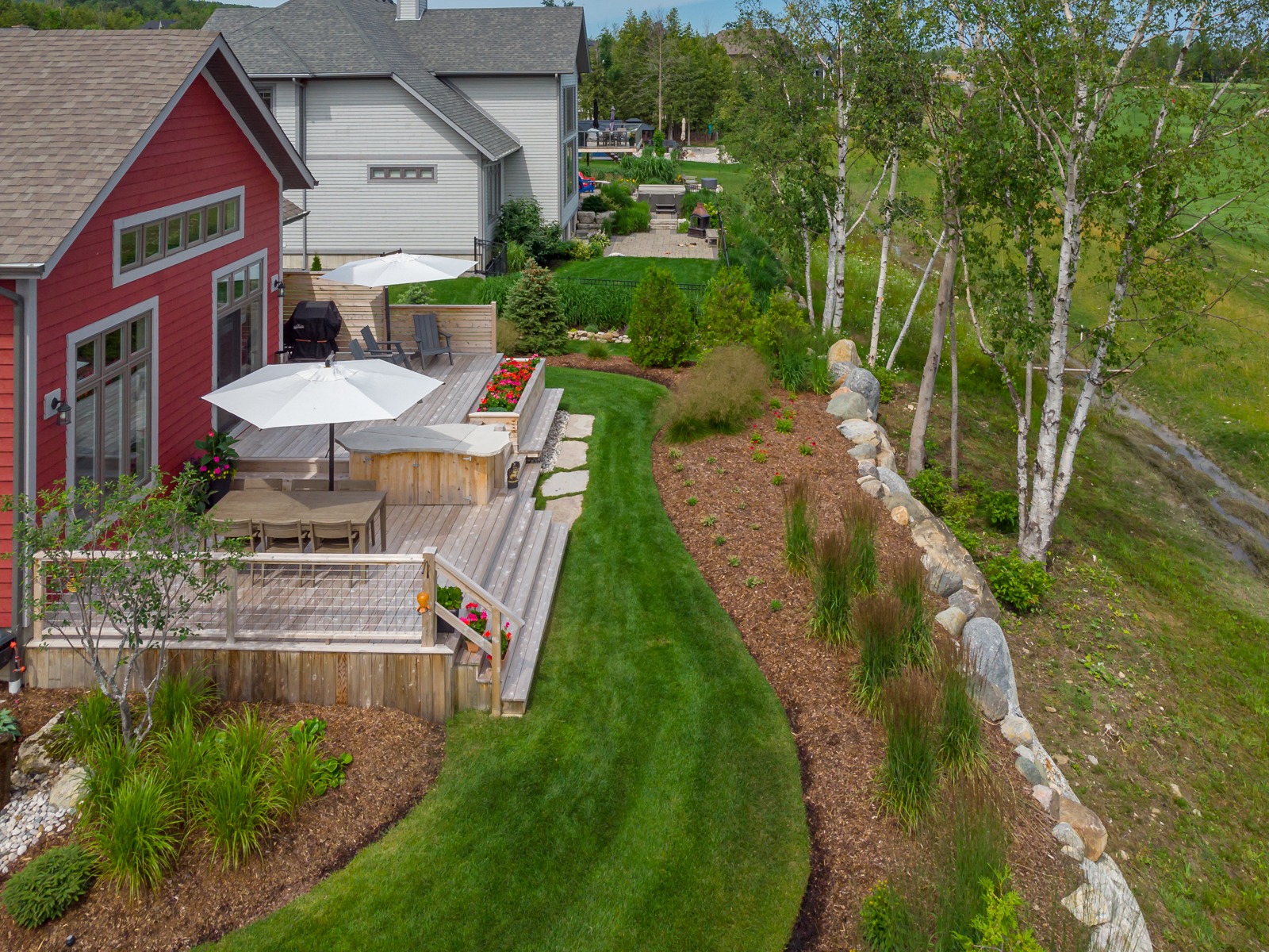 Modern backyard with deck, lawn, and stone wall