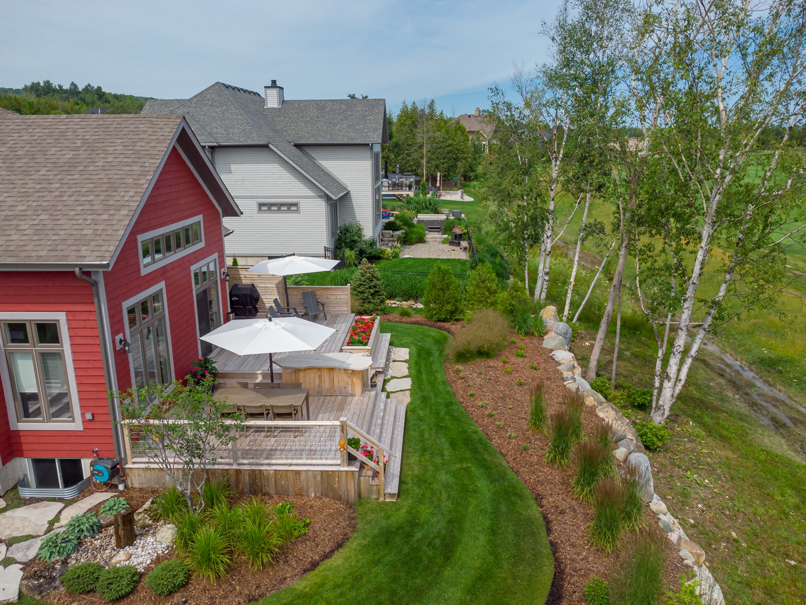 Landscaped backyard with deck and red house