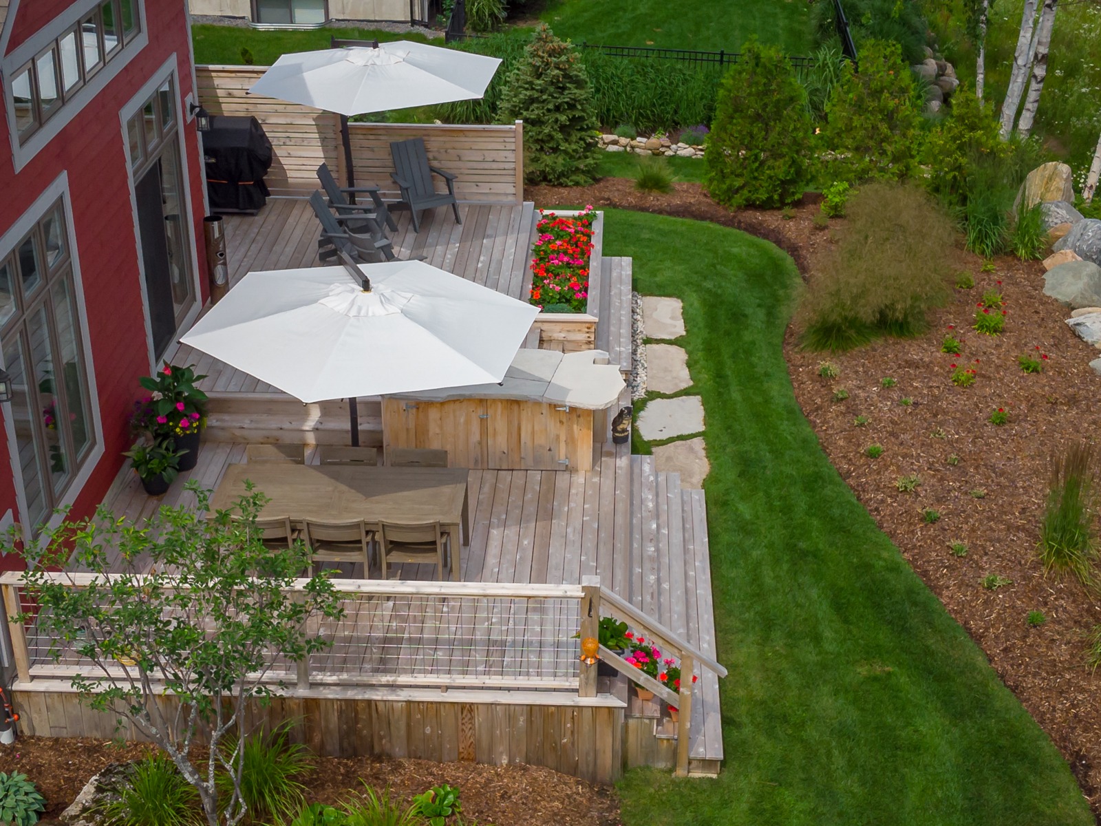 Landscaped backyard with wooden deck and patio umbrellas