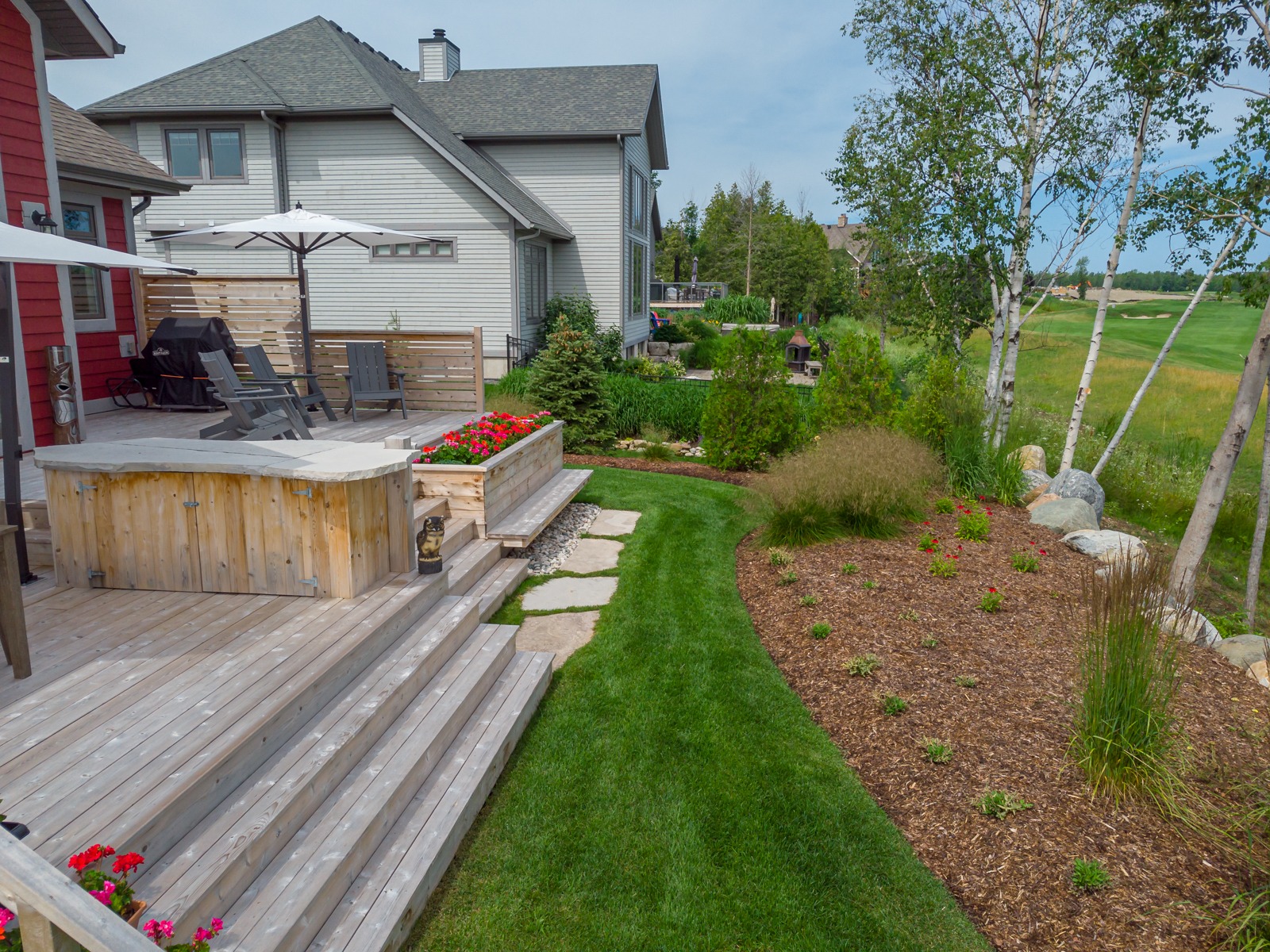 Landscaped backyard with wooden deck and patio seating