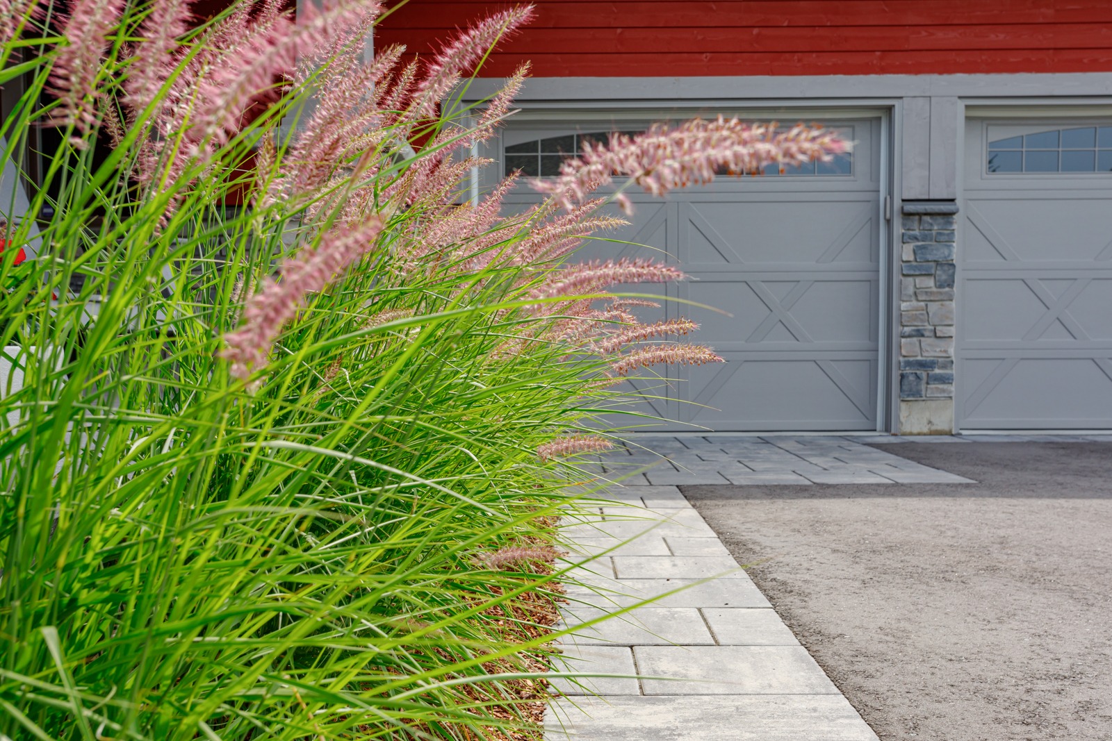 Ornamental grasses beside driveway and gray garage doors