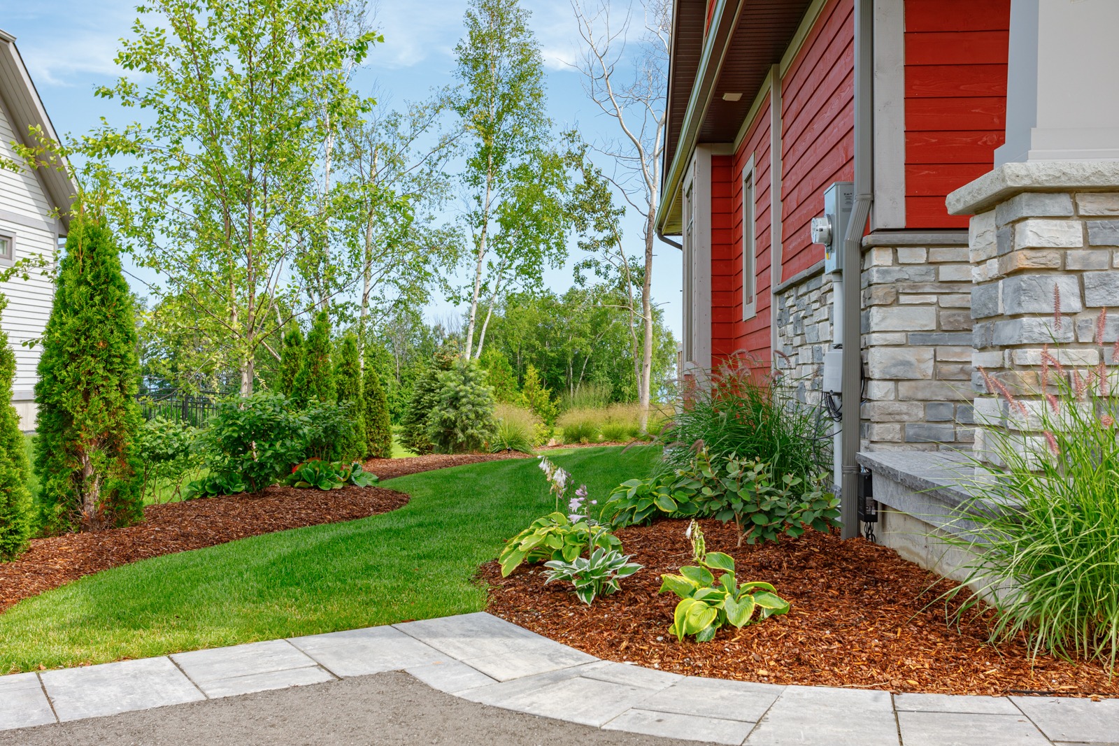 Landscaped backyard beside red house with stone exterior