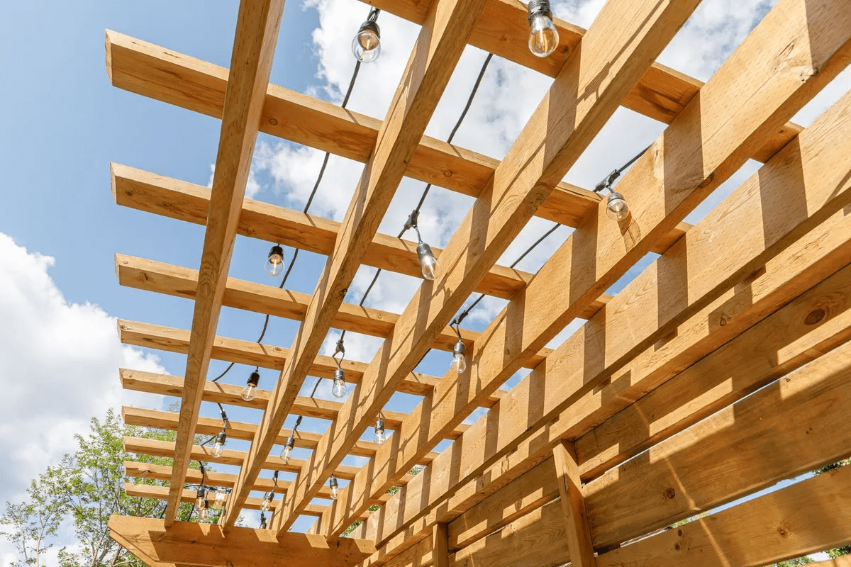 Wooden pergola with string lights against blue sky