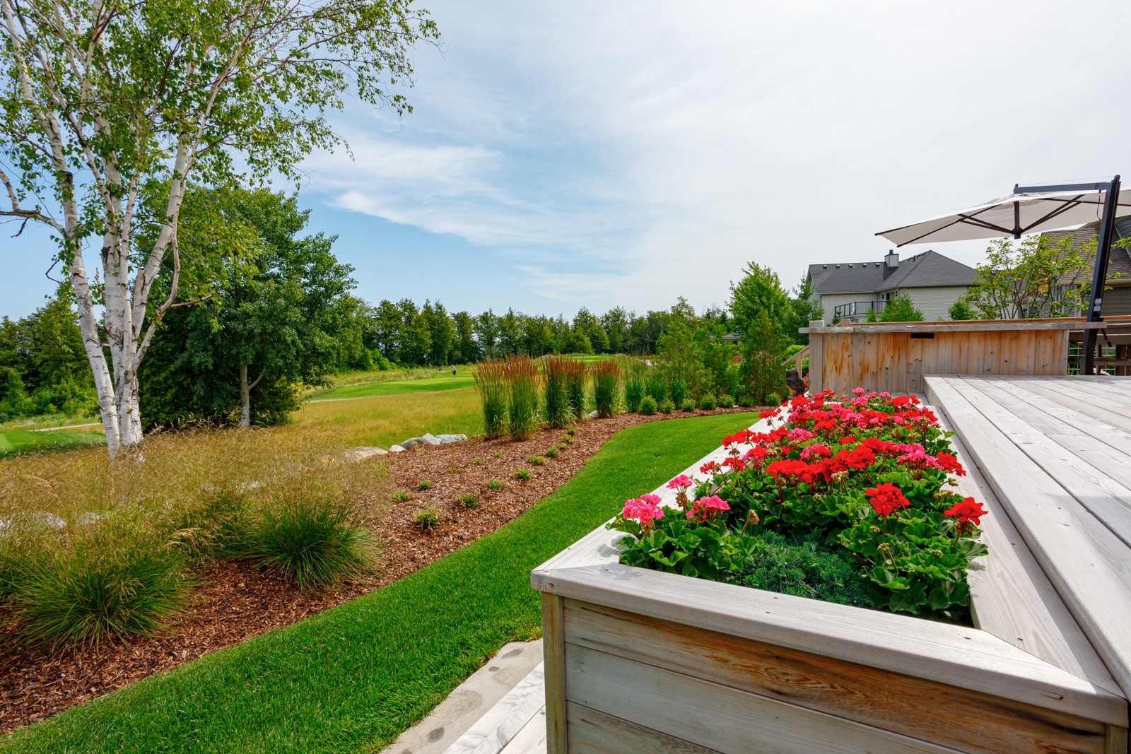 Landscaped backyard with deck and red flowers