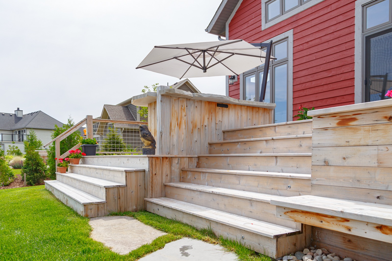 Tiered wooden deck with umbrella and red house