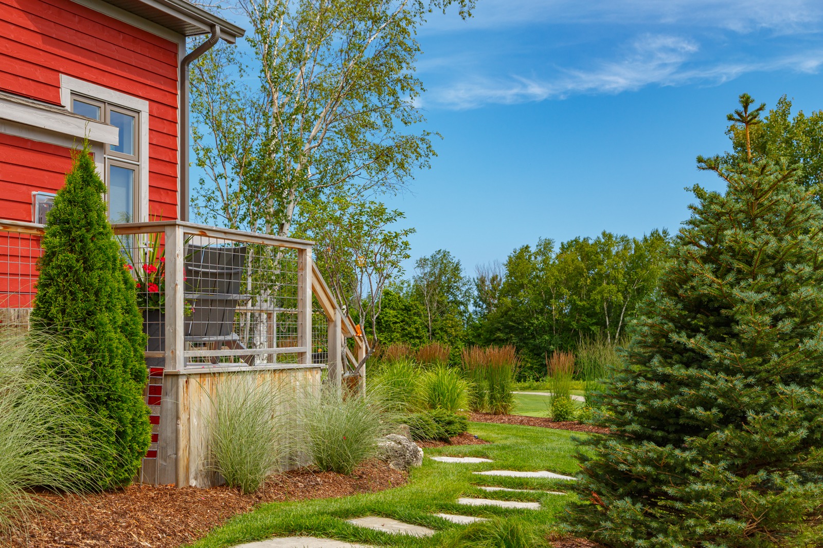 Red house porch with landscaped garden and trees