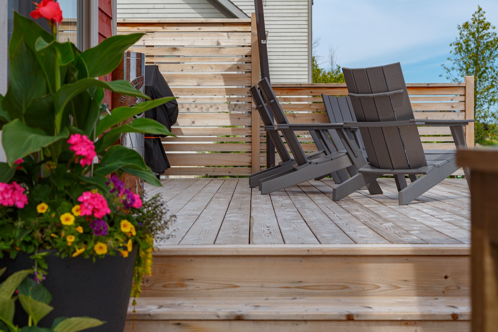 Wooden deck with Adirondack chairs and colorful flowers
