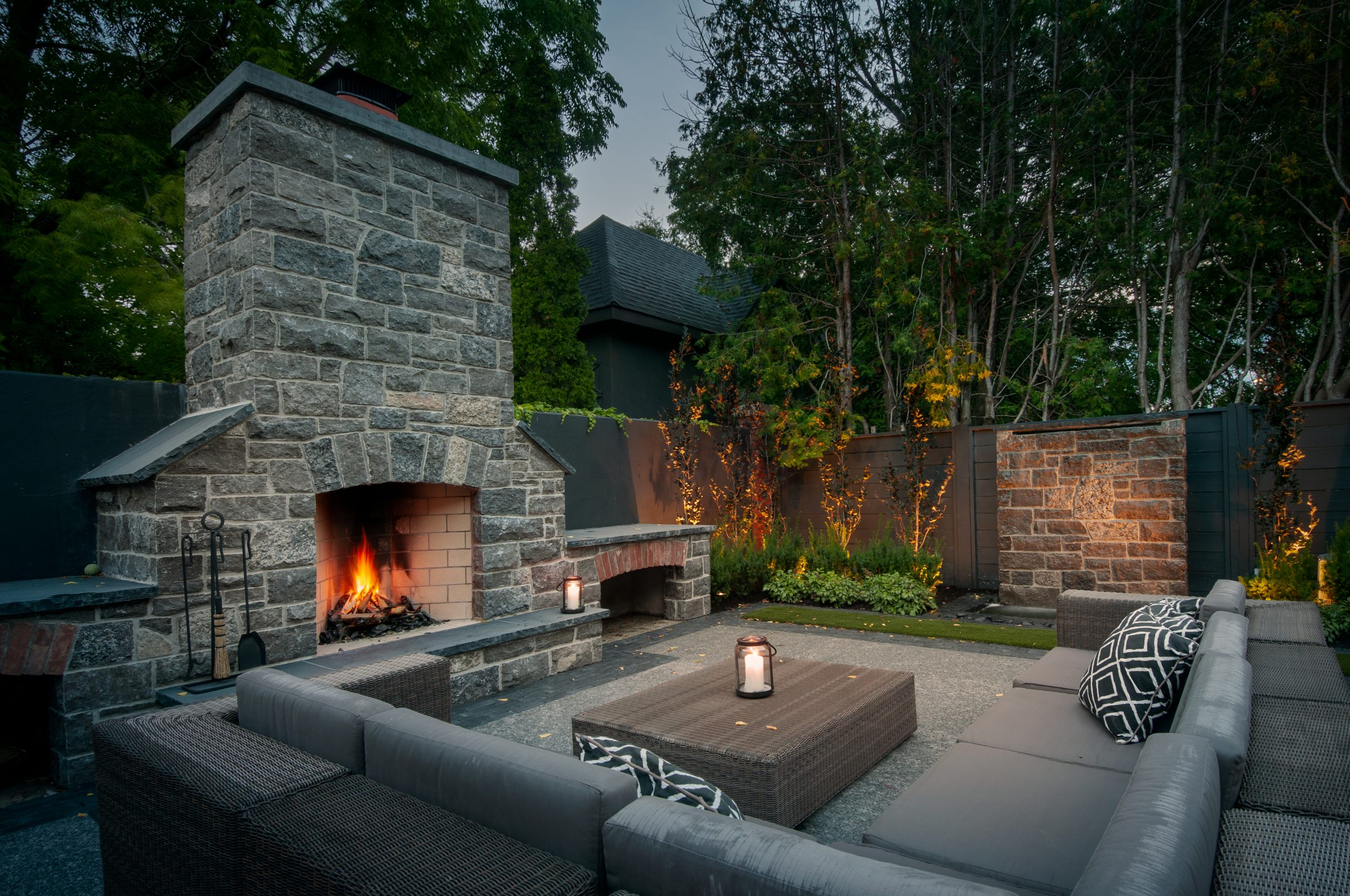 Cozy outdoor patio with stone fireplace at dusk