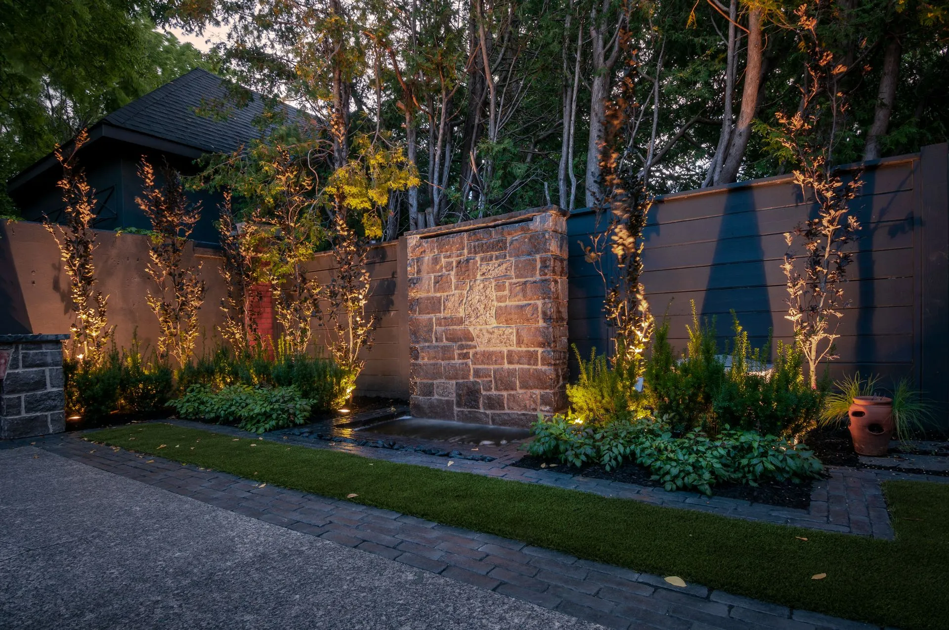 Modern backyard with illuminated stone water feature