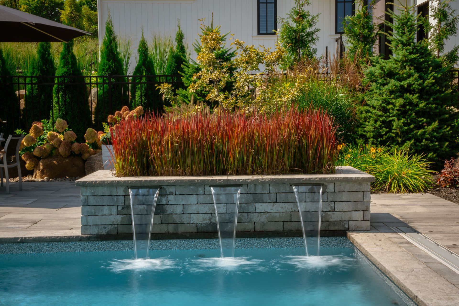 Backyard pool with stone waterfall and garden landscaping