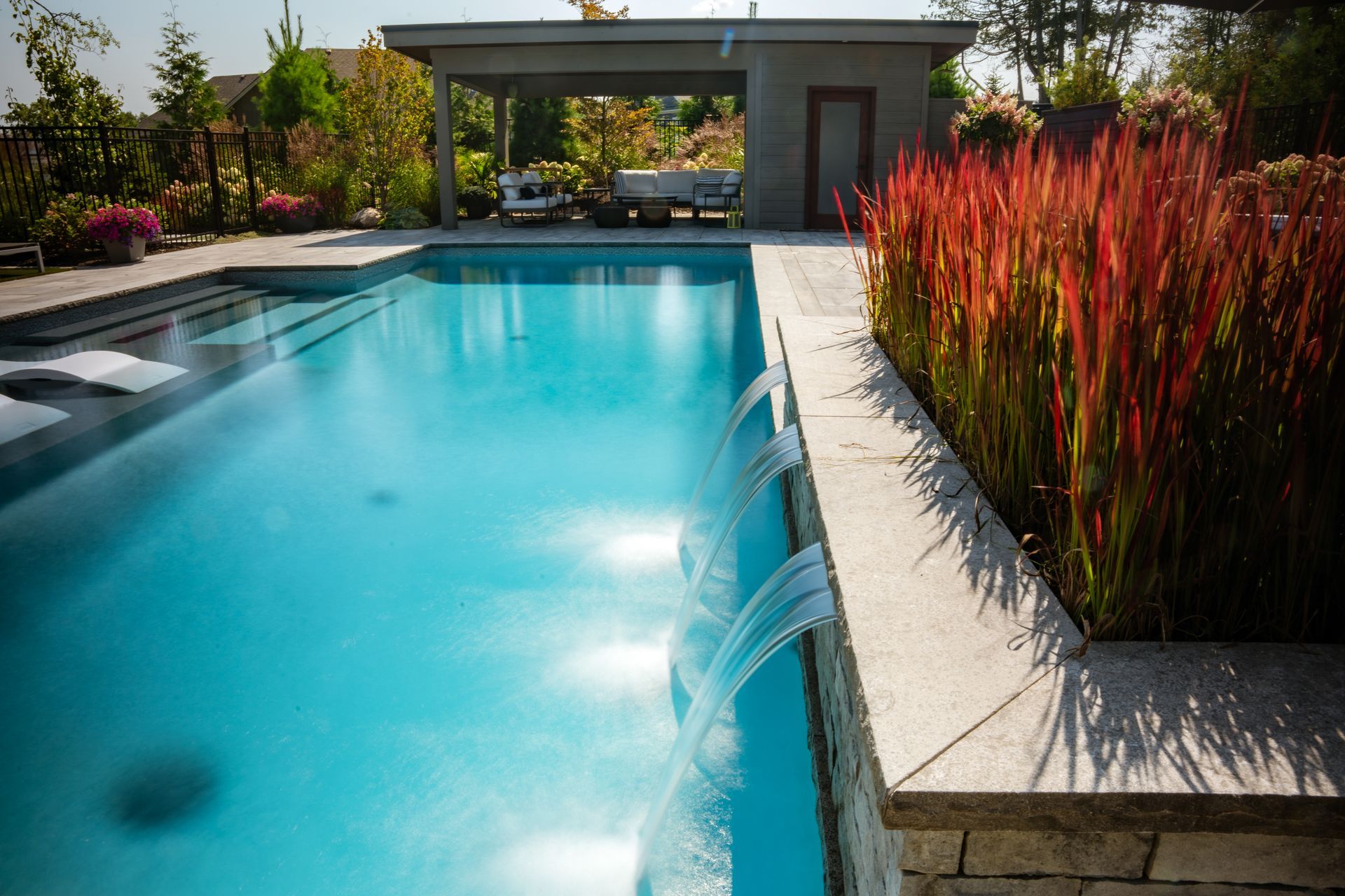 Modern backyard pool with water features and cabana