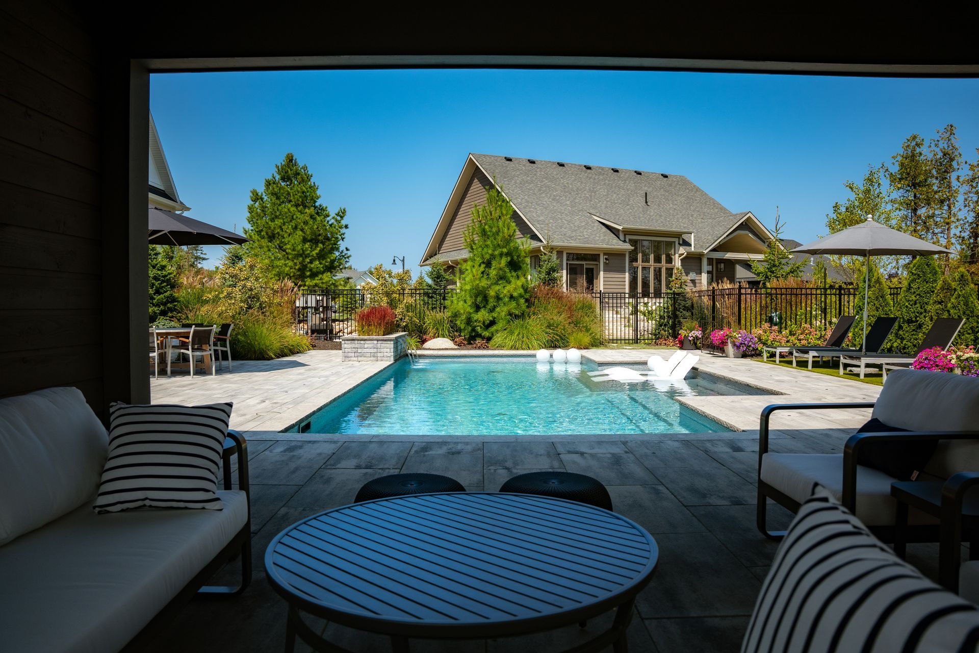 Modern backyard pool with patio seating and umbrellas