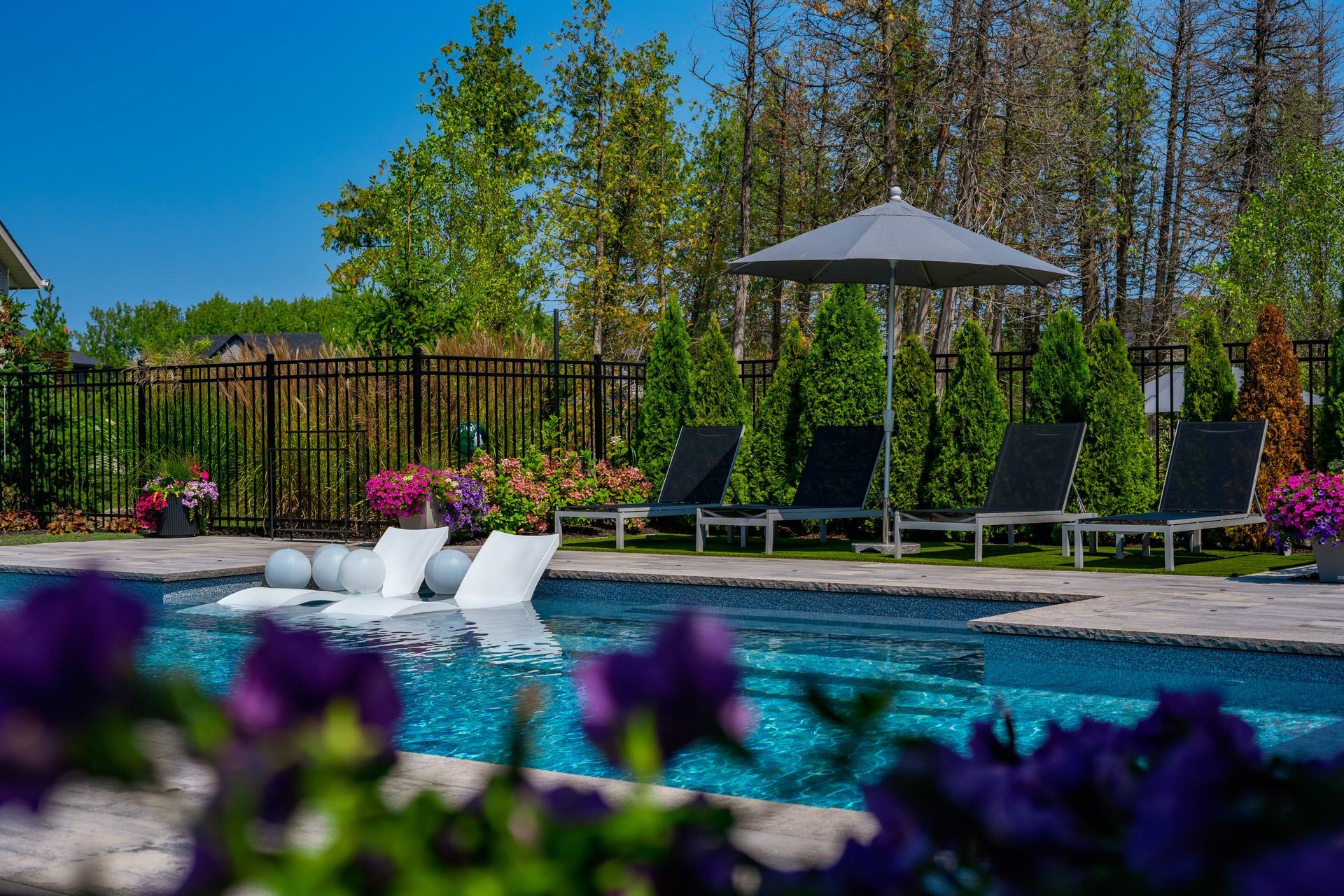 Landscaped backyard pool with loungers and umbrella