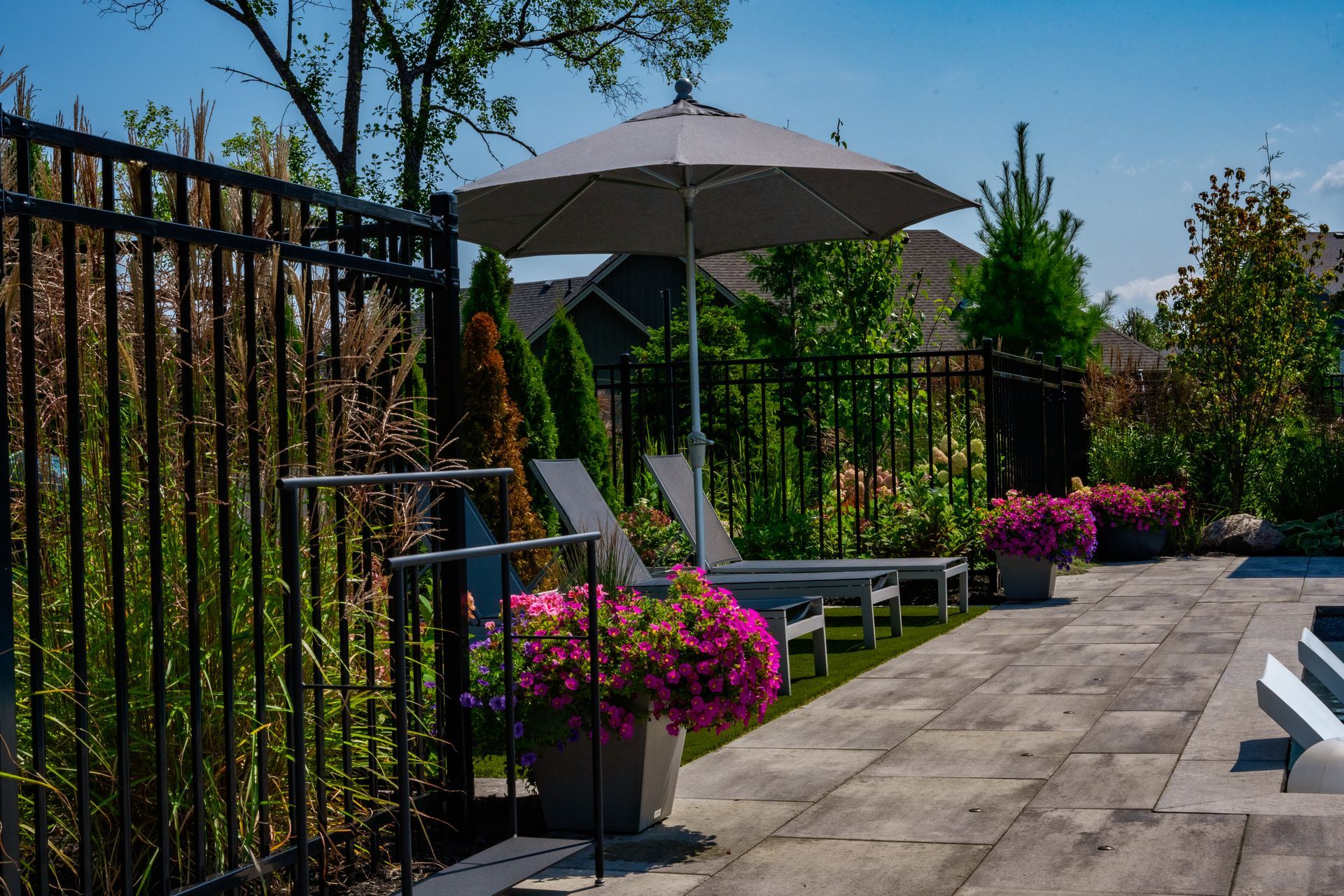 Landscaped backyard patio with lounge chairs and umbrella