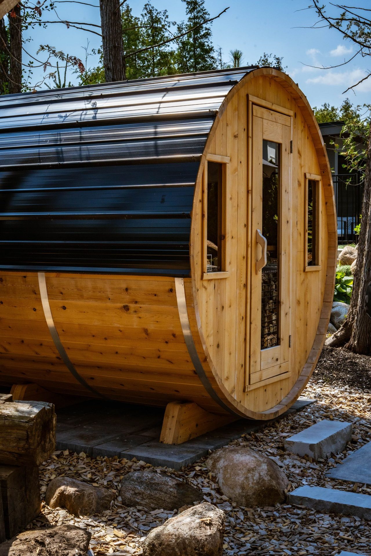 Barrel-shaped wooden outdoor sauna with metal roof