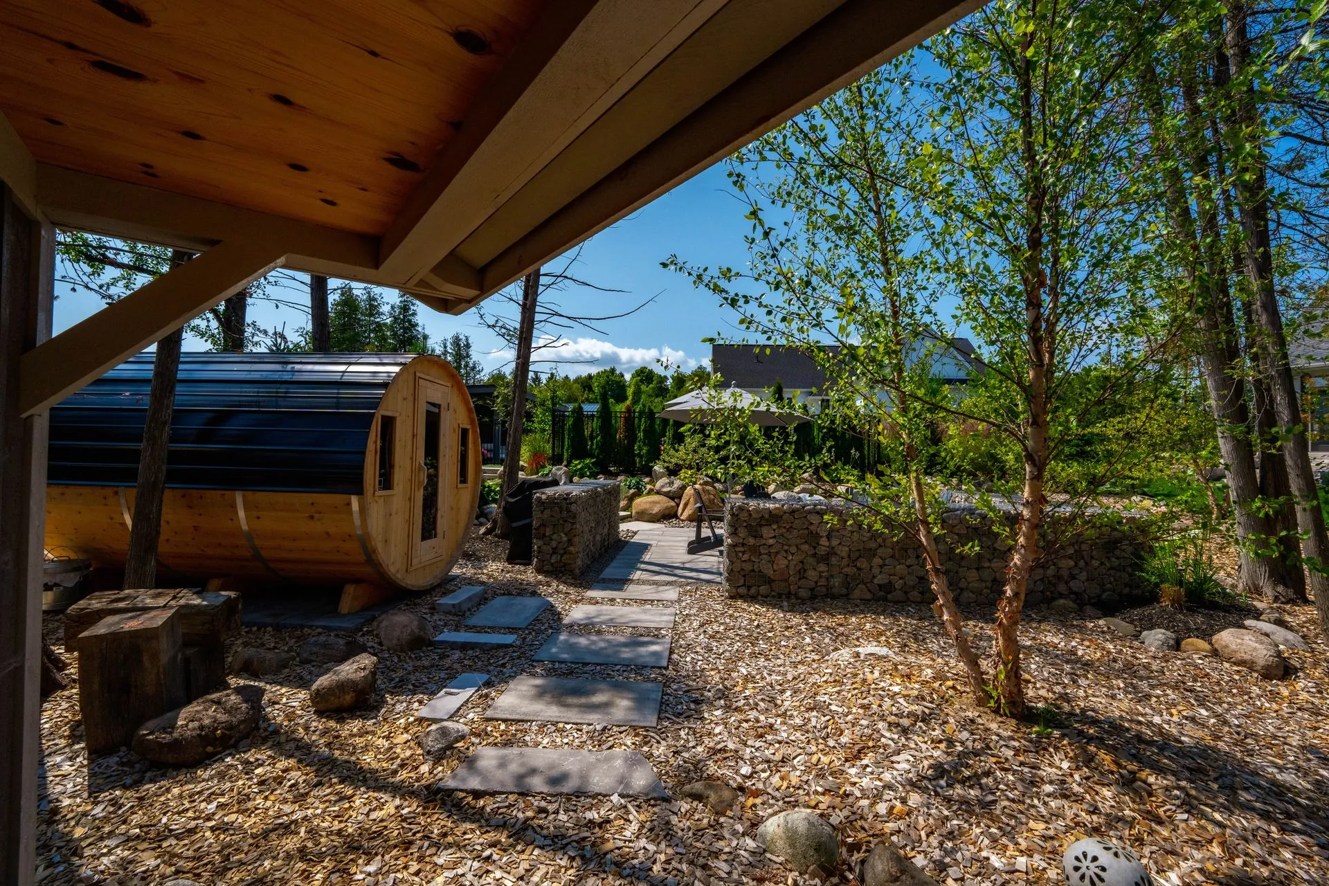 Backyard barrel sauna and stone patio garden