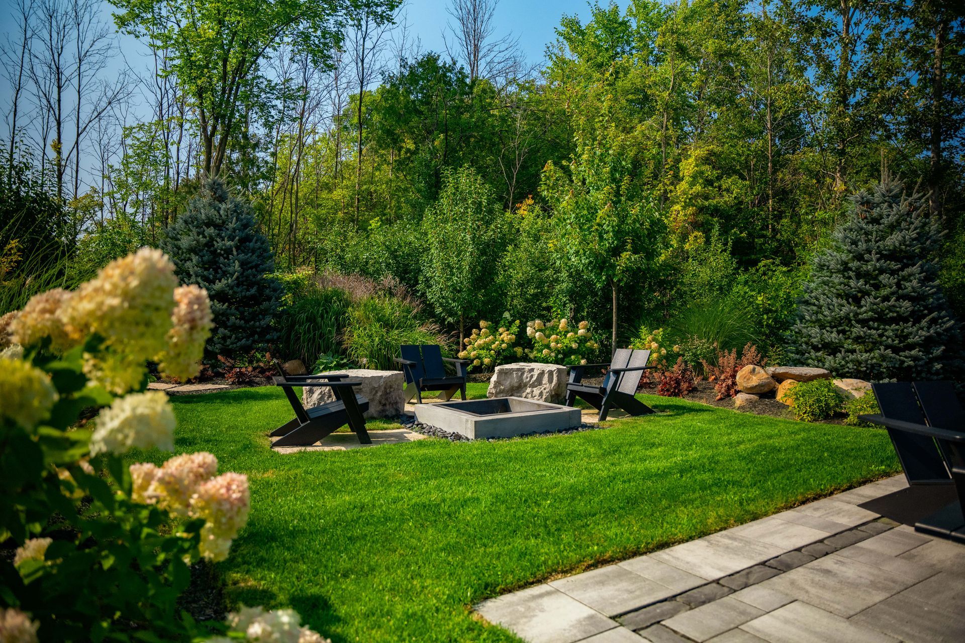 Landscaped backyard with modern chairs and fire pit