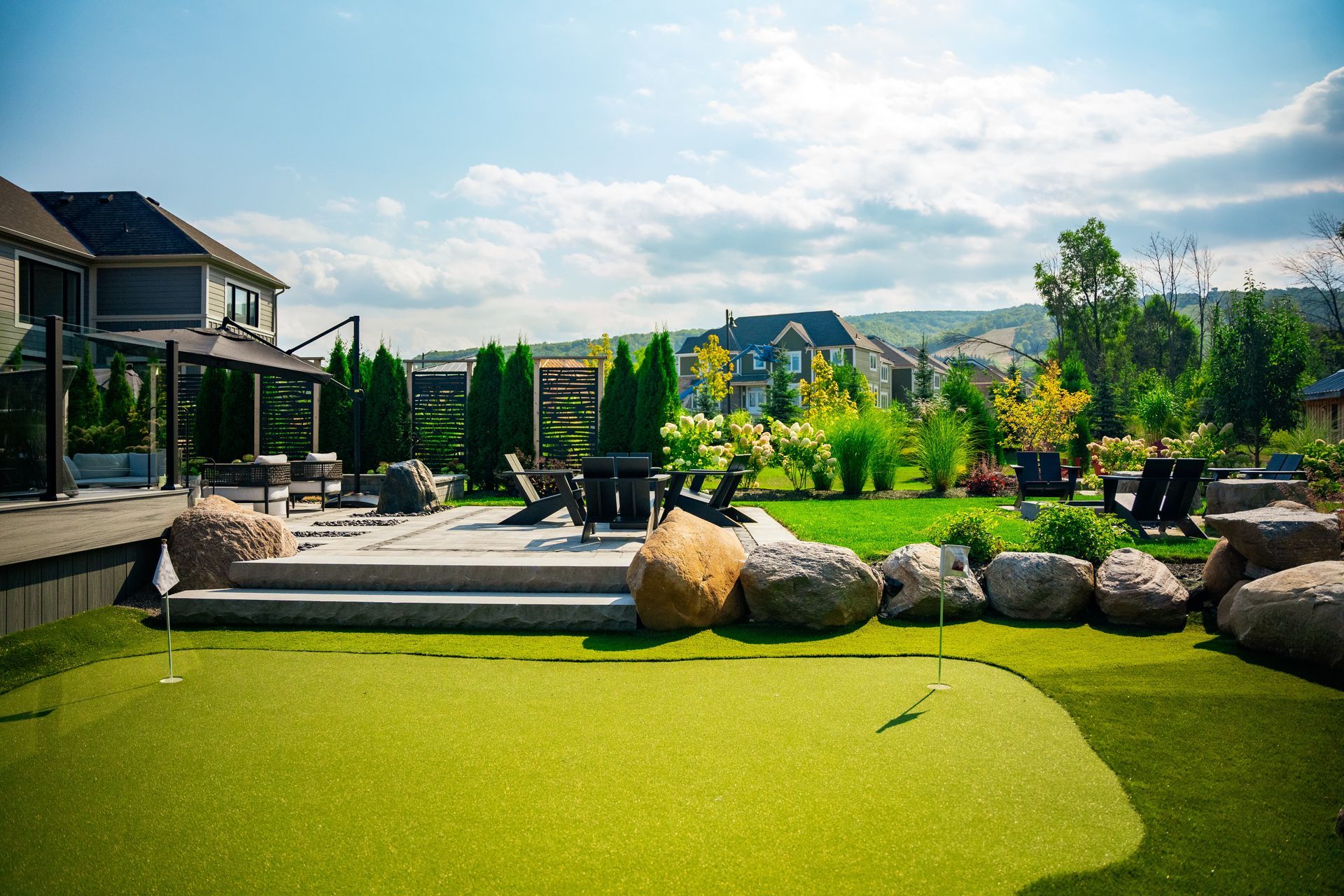 Landscaped backyard with patio, fire pit, and putting green