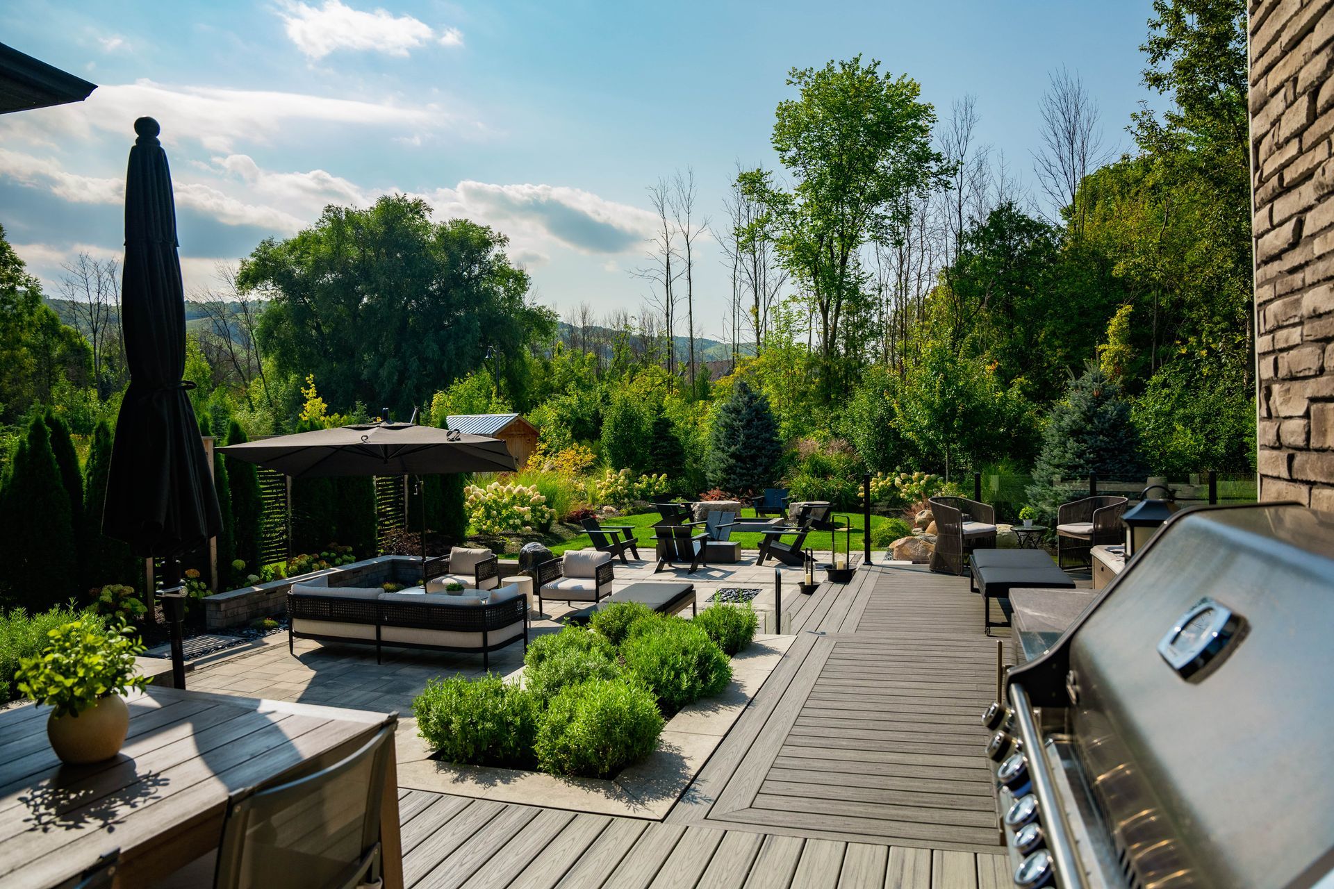 Landscaped backyard patio with seating and grill
