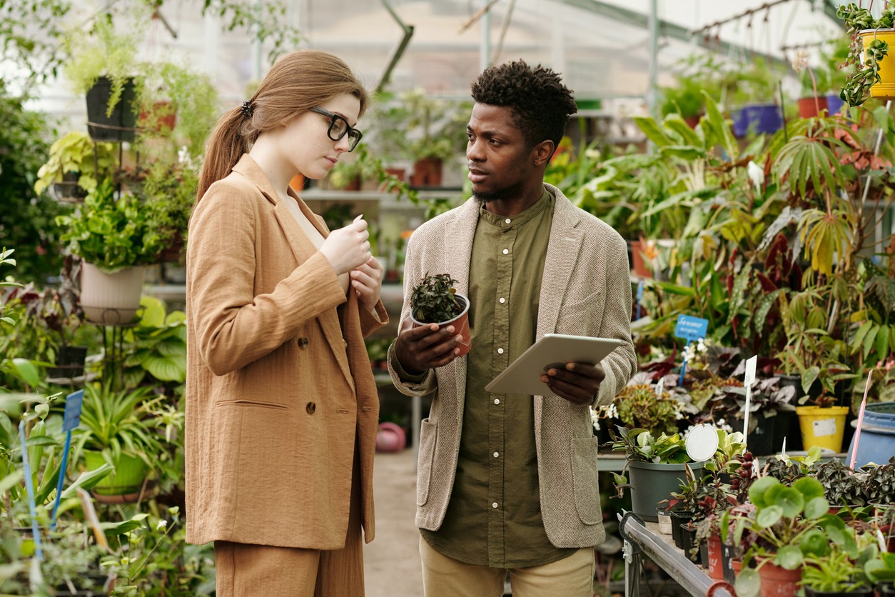 Two people discussing plants in greenhouse