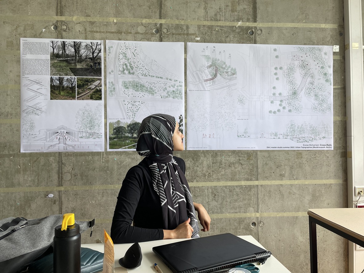 Woman reviewing architectural posters on concrete wall