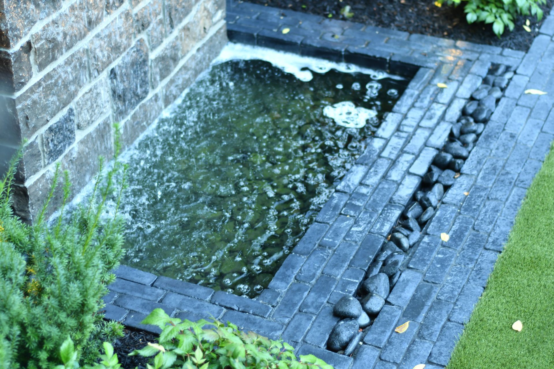 Small backyard pond with stone waterfall feature