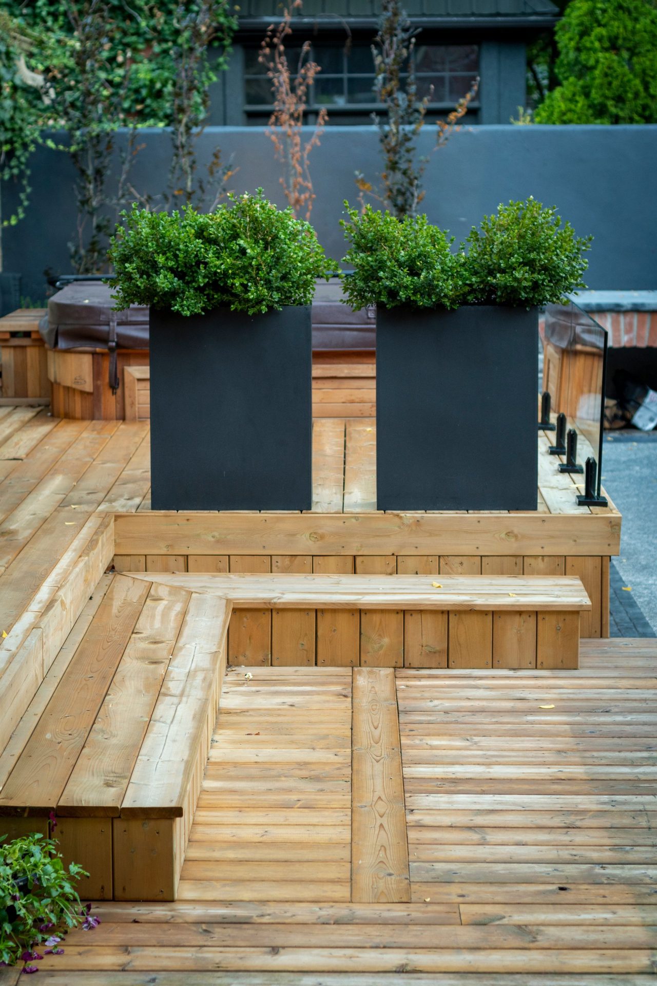 Modern wooden deck with black planters and shrubs