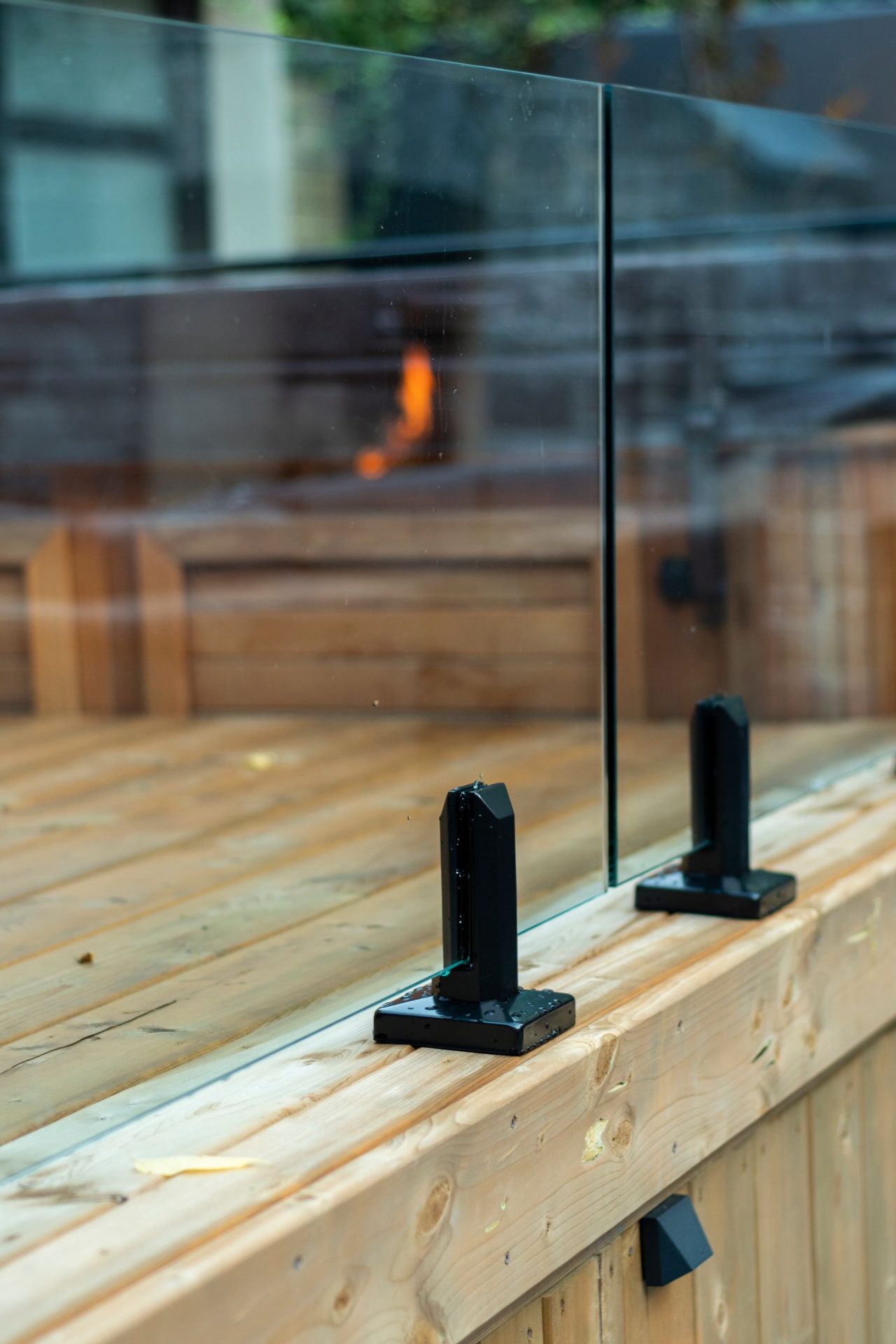 Glass deck railing with black metal clamps